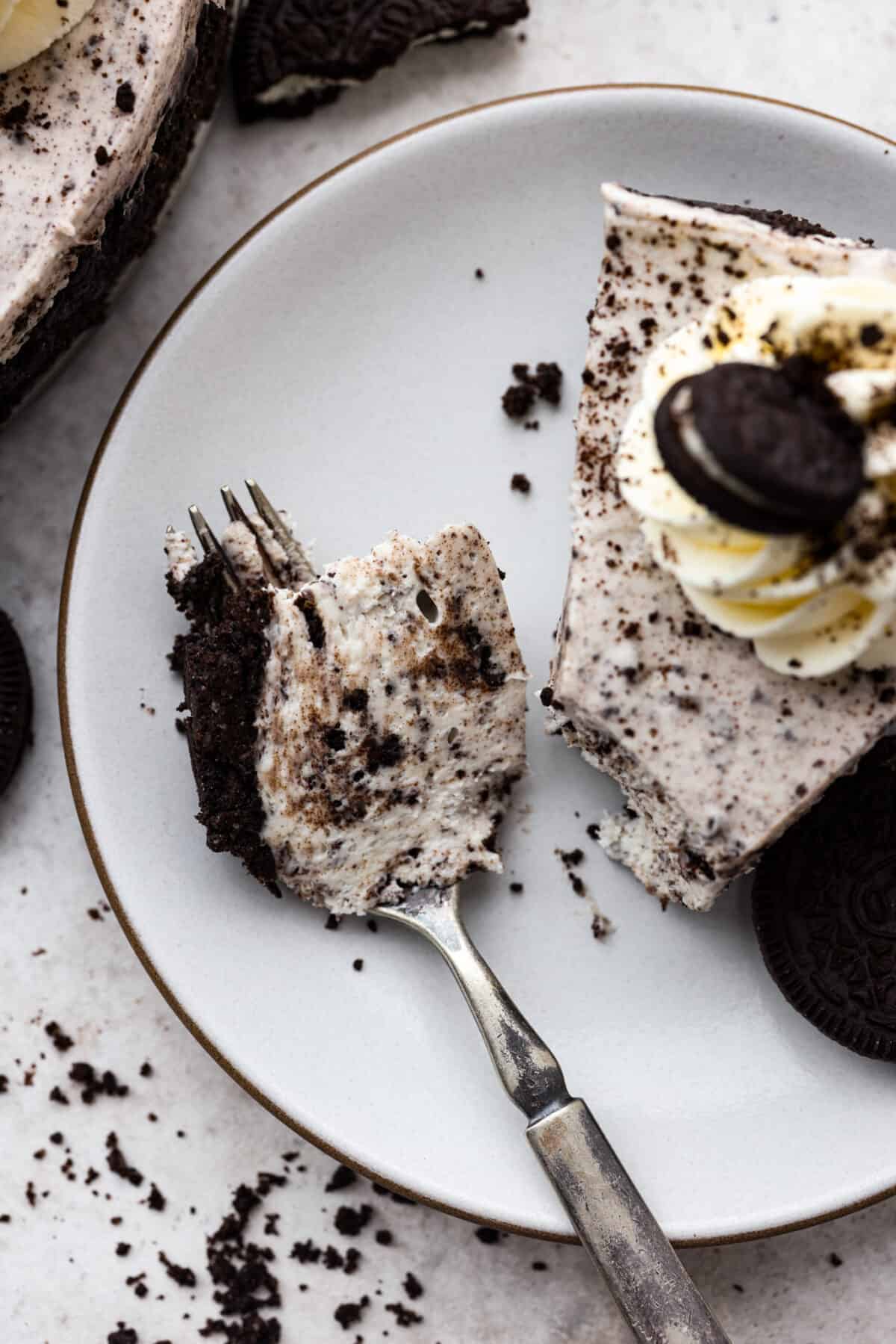 Indulge in pure dessert delight with this no-bake Oreo cheesecake! It has a creamy filling packed with crushed Oreos on a crust made of even more Oreos—talk about dreamy! And the best part? It's a breeze to whip up, no need to turn on your oven! Taking a bite of Oreo cheesecake.