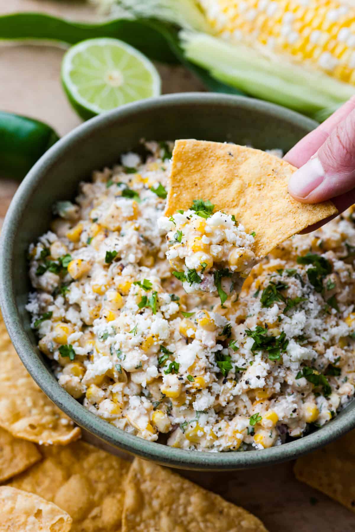 Dive into the irresistible taste of Mexican street corn with this easy-to-make dip. Charred corn, green chilies, spices, and creamy mayo blend perfectly for a delicious appetizer for any occasion! A tortilla chip scooping up some dip.