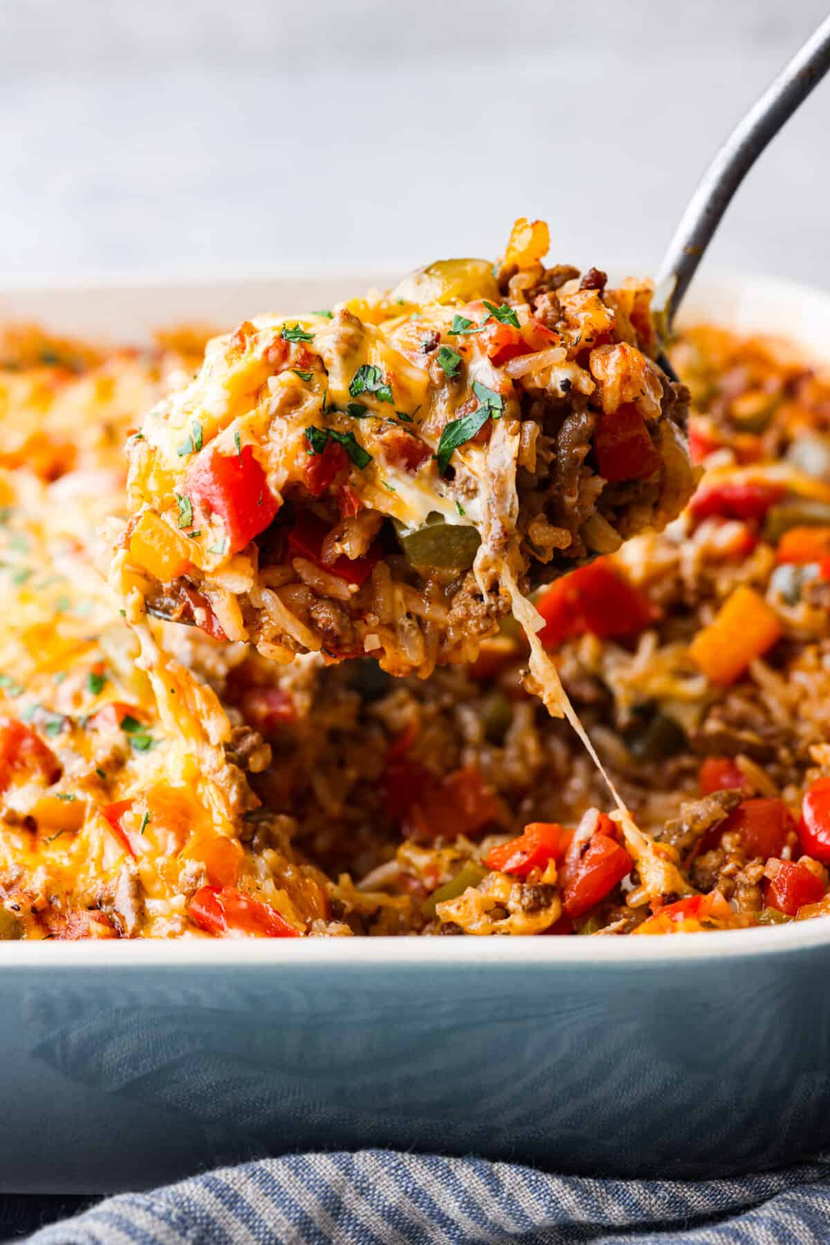 All the hearty, flavorful goodness of a stuffed pepper in one easy-to-make casserole! Stuffed pepper casserole is easy, cheesy, and packed to the brim with delicious seasoned rice and vegetables. Closeup of a scoop of stuffed pepper casserole.