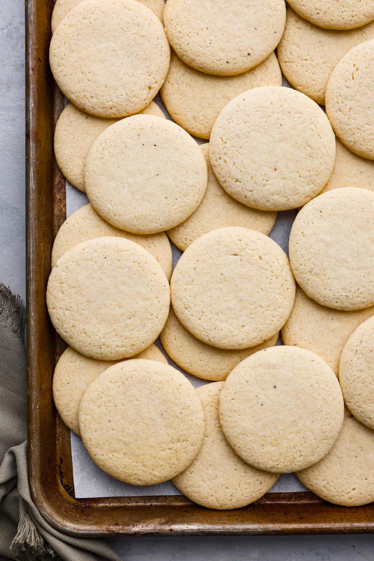 Delicately crumbly and a little bit sweet, these tea cakes are the perfect afternoon snack! They're super simple, but so irresistible. Make a cup of your favorite tea to serve with them and enjoy! Overhead shot baked tea cakes on cookie sheet.