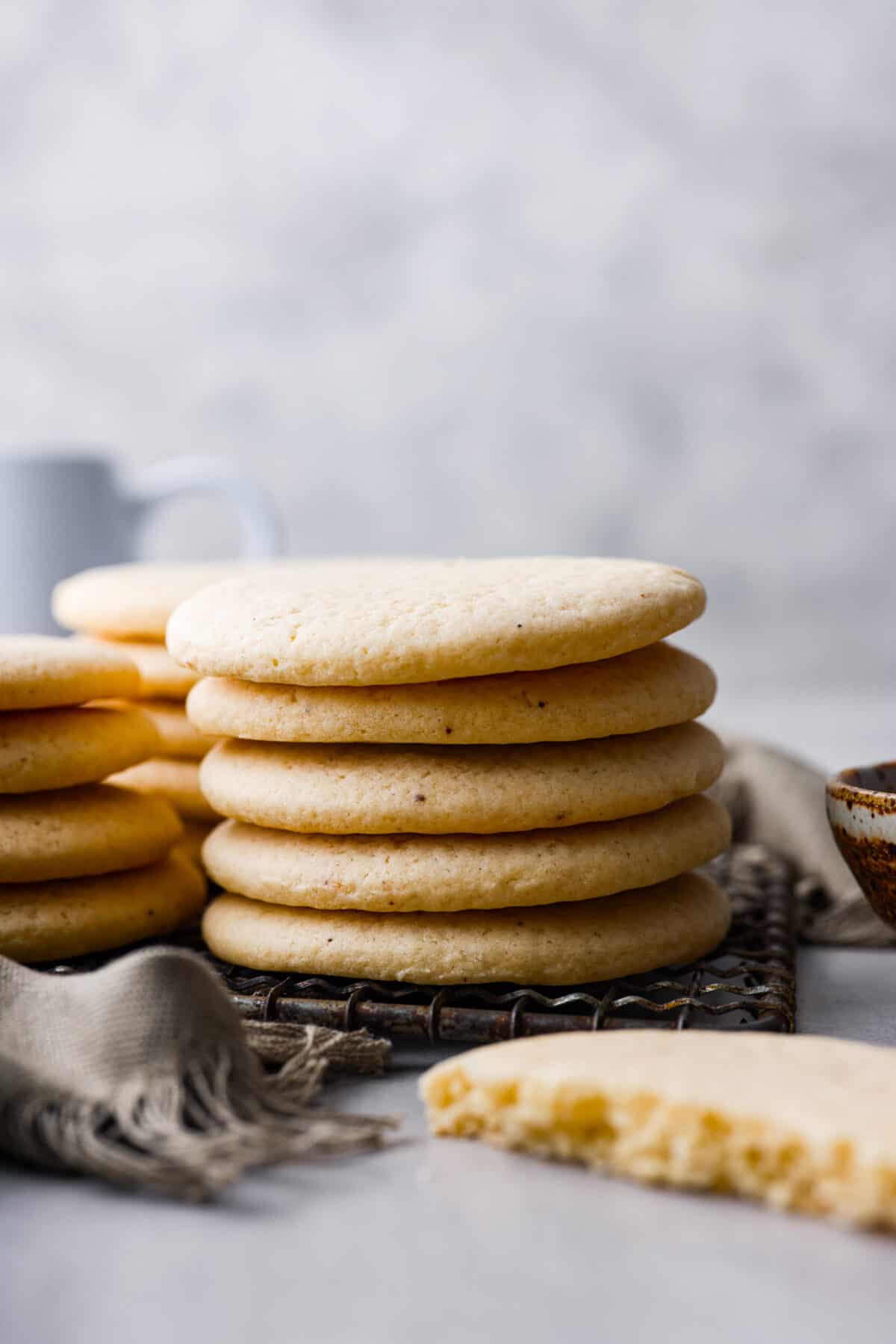 Delicately crumbly and a little bit sweet, these tea cakes are the perfect afternoon snack! They're super simple, but so irresistible. Make a cup of your favorite tea to serve with them and enjoy! Side shot of a stack of tea cakes on a cooling rack.