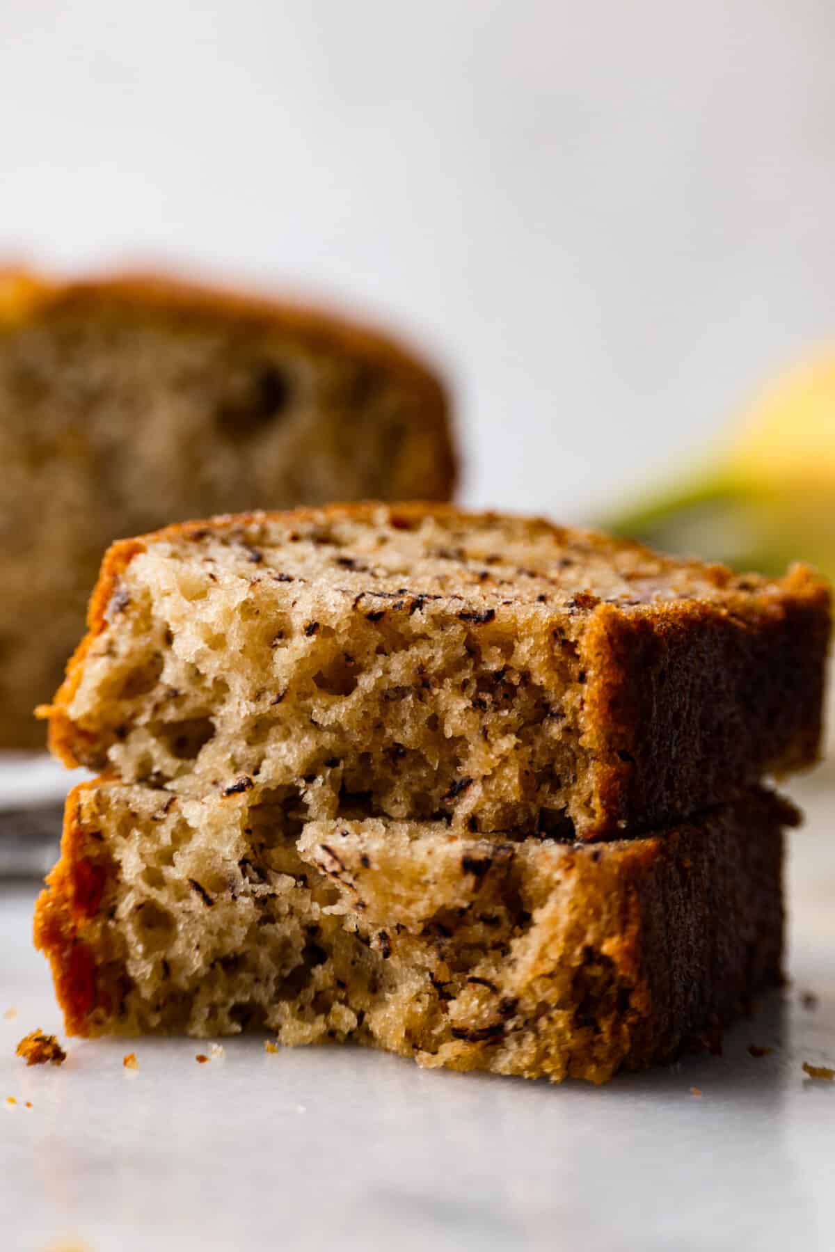 Make your homemade banana bread even more tender and delicious by adding in sour cream! This recipe is the best youโll try, and you wonโt be able to stop at one piece! Closeup of 2 thick slices stacked on top of each other.