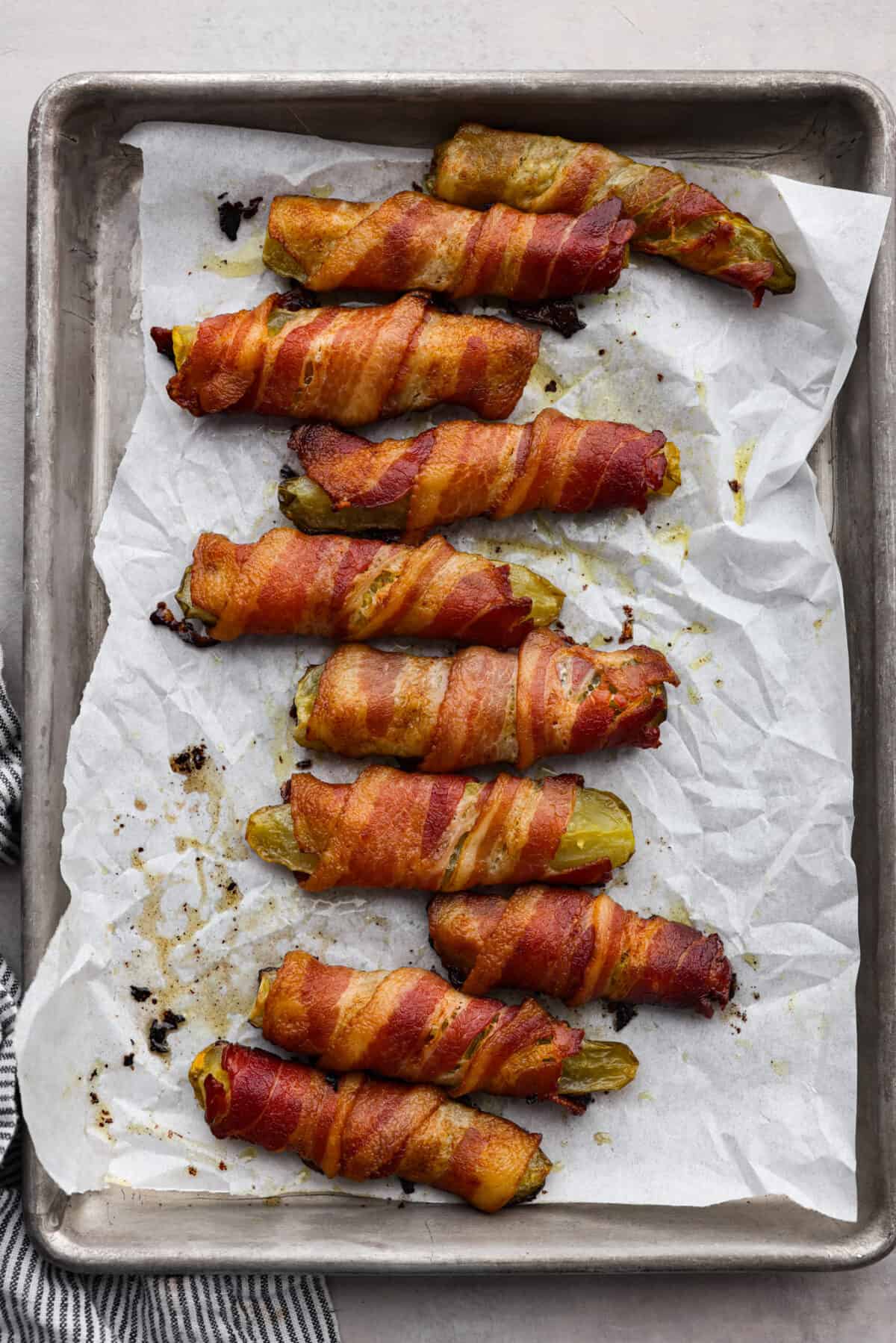 Calling all pickle lovers! Meet your new favorite appetizer. These bacon wrapped pickles are the perfect combination of tangy, crunchy, and meaty, and so easy to devour! Bacon wrapped pickles on a baking sheet.