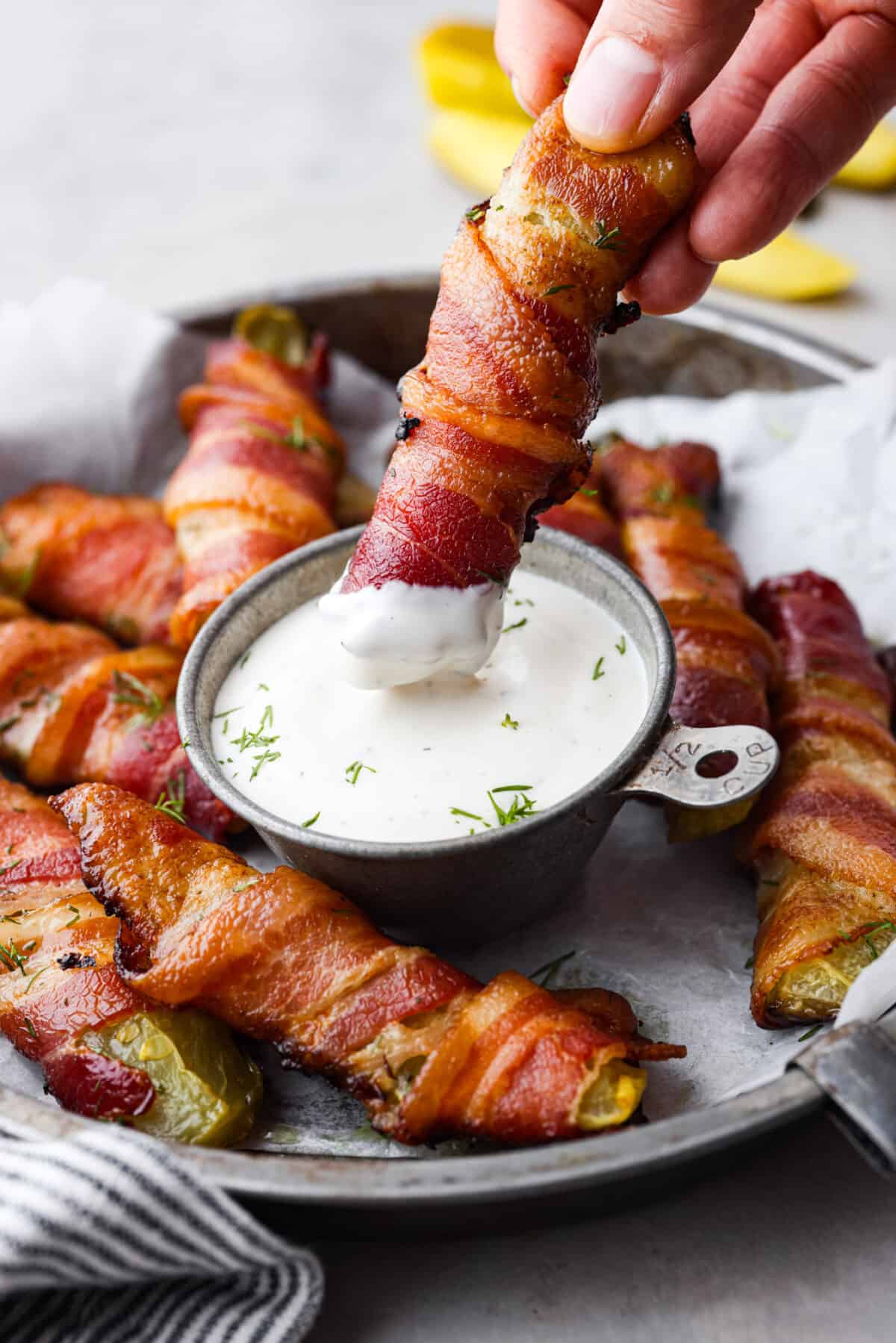 Calling all pickle lovers! Meet your new favorite appetizer. These bacon wrapped pickles are the perfect combination of tangy, crunchy, and meaty, and so easy to devour! Dipping a pickle into ranch.