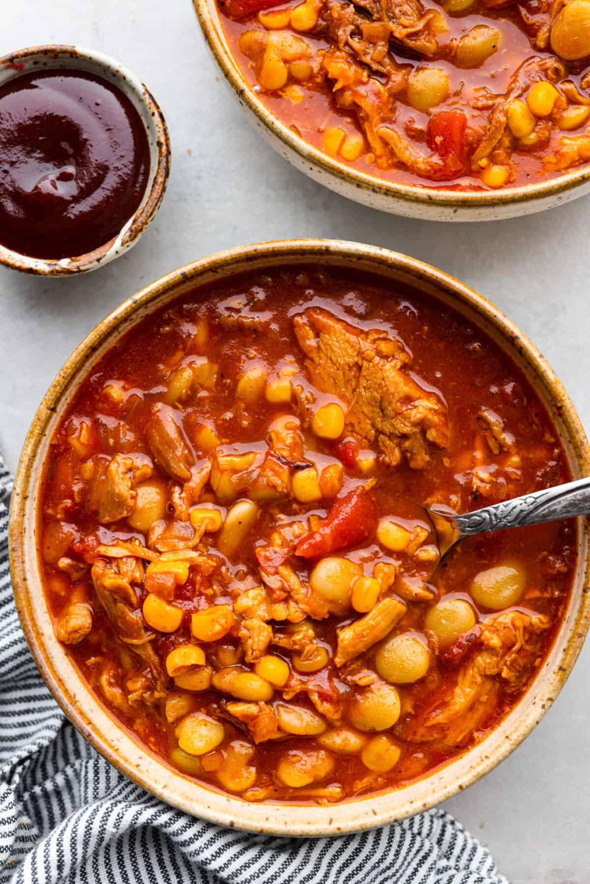 Brunswick stew has sizzling onions, garlic, BBQ sauce, and tender pulled pork all in one pot! Add a bit of cayenne for some zing and sweet corn and lima beans for texture. This combination of ingredients is so hearty and makes the best fall meal! Top-down view of Brunswick stew served in a stoneware bowl.