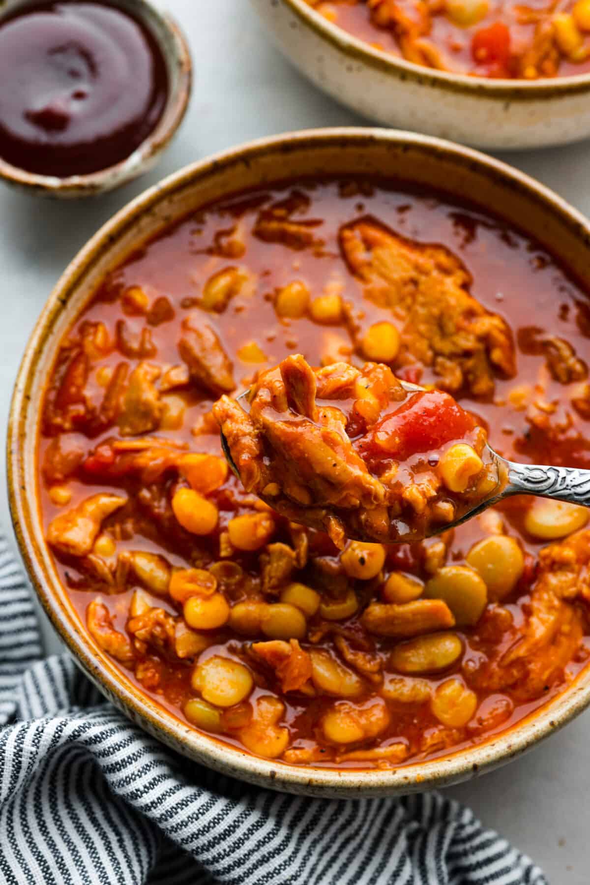 Brunswick stew has sizzling onions, garlic, BBQ sauce, and tender pulled pork all in one pot! Add a bit of cayenne for some zing and sweet corn and lima beans for texture. This combination of ingredients is so hearty and makes the best fall meal! An individual serving of the soup made of bbq sauce, pulled pork, corn, and fire-roasted tomatoes.