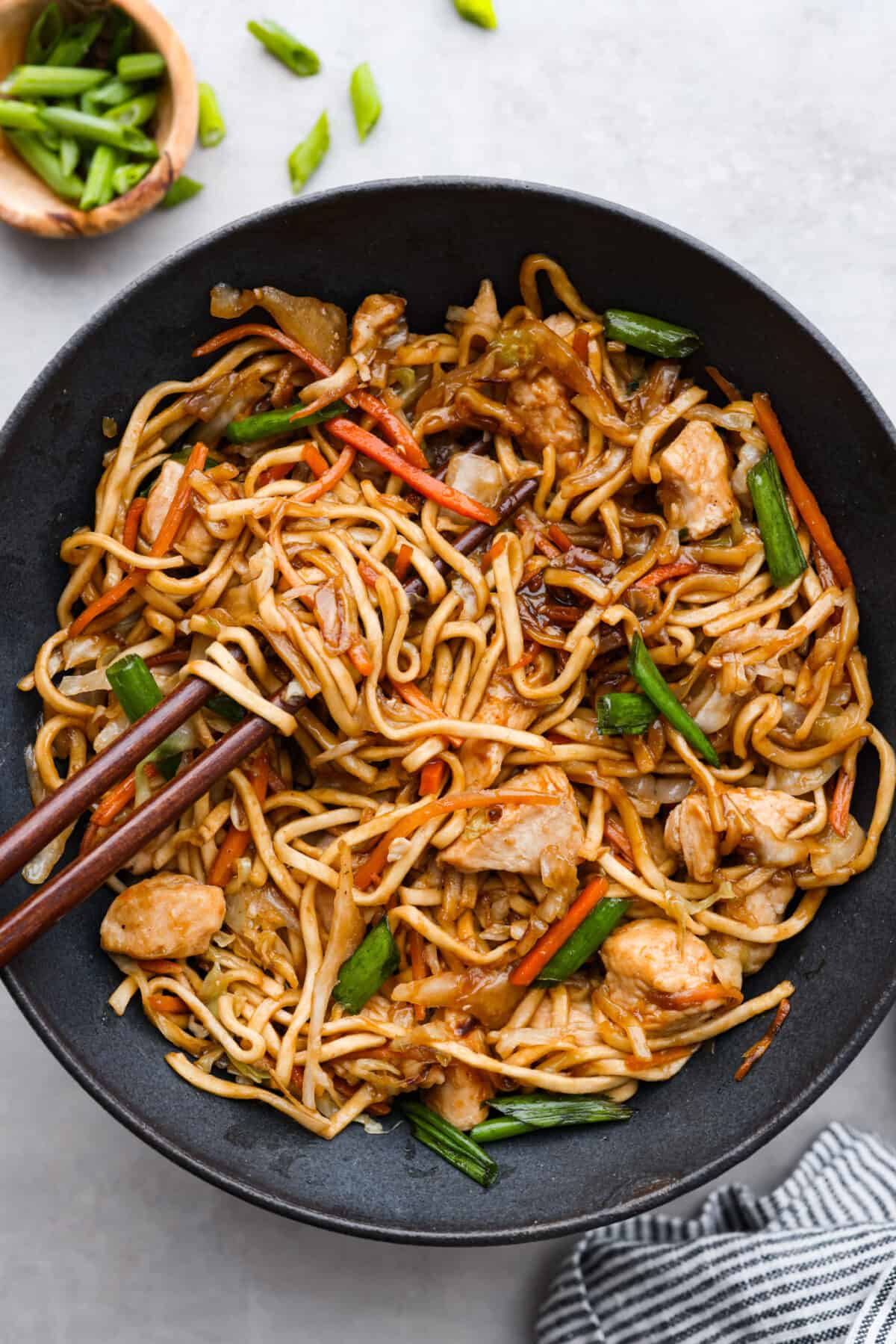 This delicious Chicken Chow Mein is perfect for a quick and easy weeknight meal that your entire family will love! It's made with fresh veggies, noodles, and sautรฉed chicken, tossed in a simple, savory glaze. Top-down view of chicken chow mein served in a black bowl.