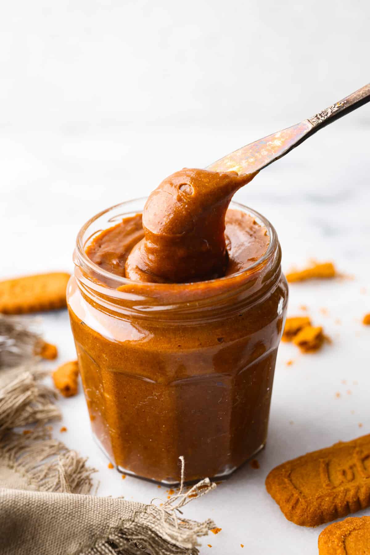 If you love Trader Joe's and you love their cookie butter, you are going to LOVE this recipe. This homemade version tastes exactly like it (except better), and then you can have it on hand all year long! Cookie butter in a jar being scooped out with a silver butter knife.