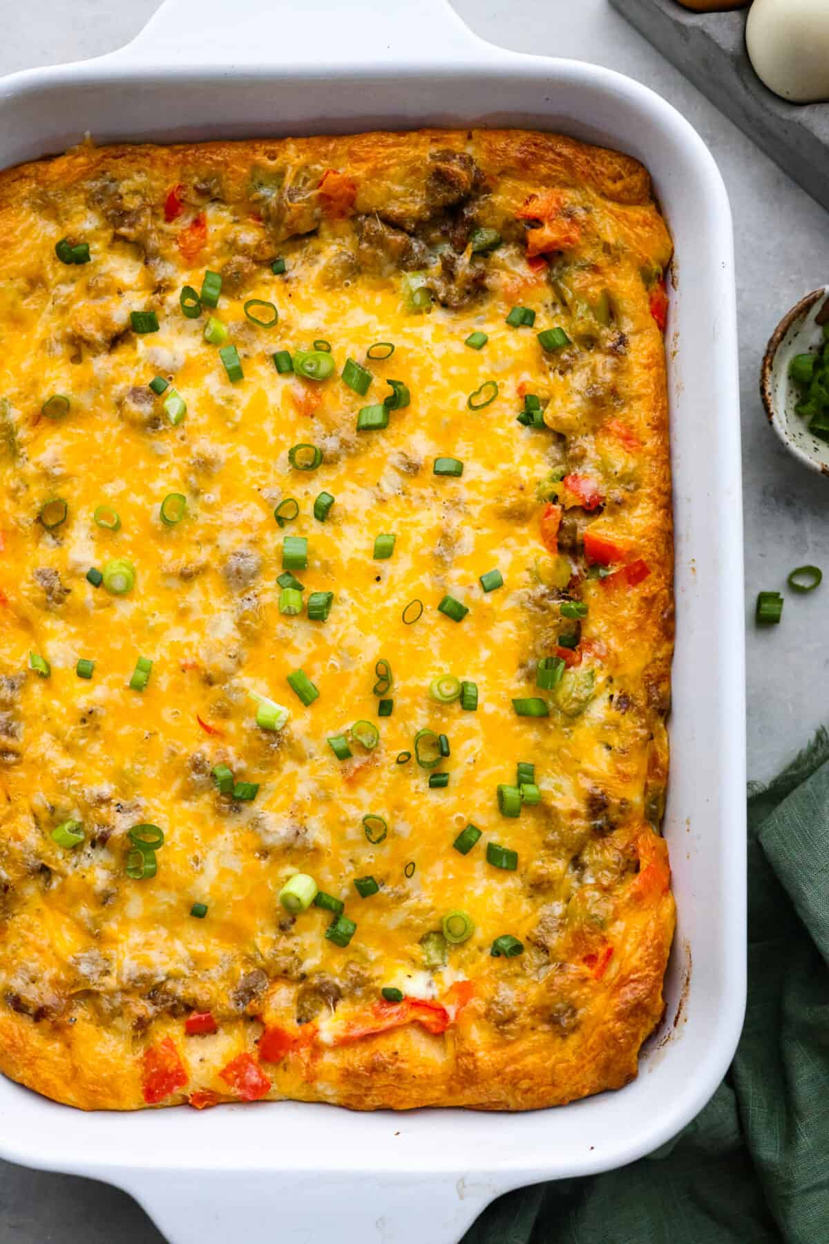 Meet crescent roll breakfast casserole: your new favorite way to use up that refrigerated crescent dough! Juicy pork sausage, eggs, chopped bell peppers, and shredded cheese get layered on top of that buttery, delicious crust. Easy to whip up in a snap, you're going to want to make it for breakfast all the time! Top-down view of a baked crescent roll breakfast casserole.