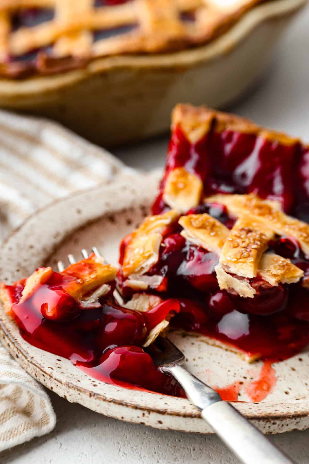 Just in time for Thanksgiving, this easy cherry pie is the perfect addition to your dessert lineup! With a buttery lattice crust and juicy filling, you won't be able to stop after one piece. Taking a bite of pie.