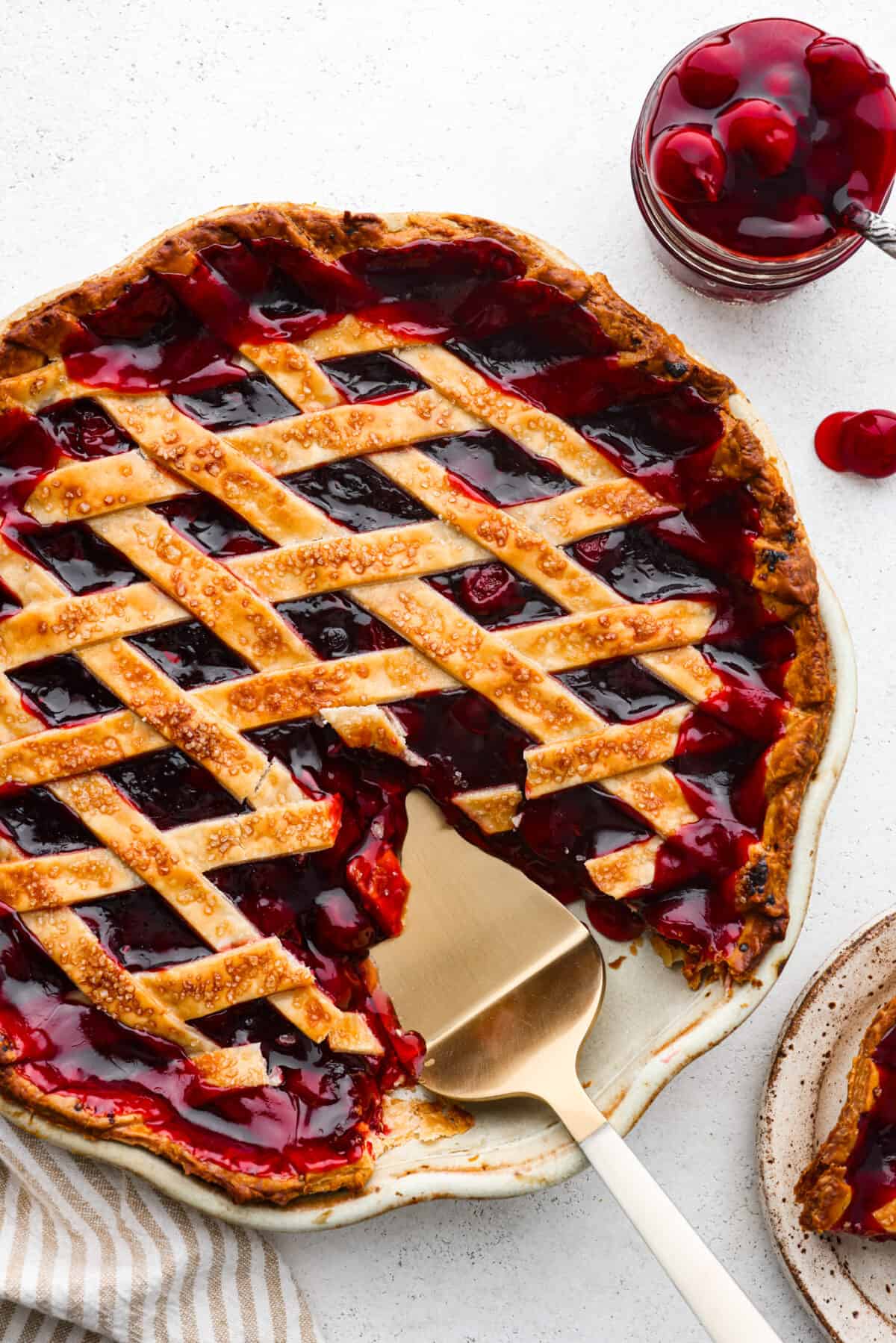 Just in time for Thanksgiving, this easy cherry pie is the perfect addition to your dessert lineup! With a buttery lattice crust and juicy filling, you won't be able to stop after one piece. Top-down view of a cherry pie with a slice cut out of it.