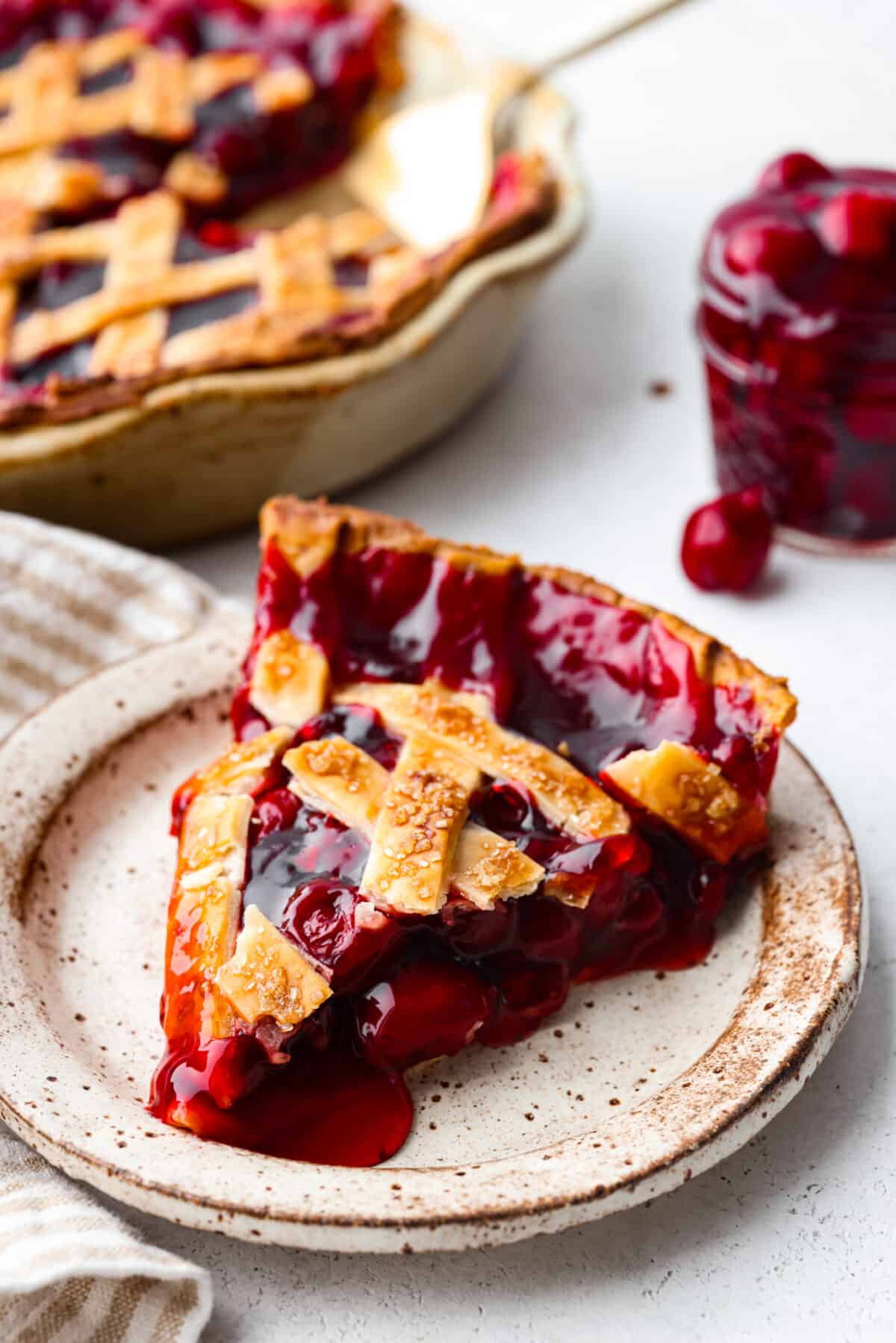 Just in time for Thanksgiving, this easy cherry pie is the perfect addition to your dessert lineup! With a buttery lattice crust and juicy filling, you won't be able to stop after one piece. A slice of cherry pie on a stoneware plate.