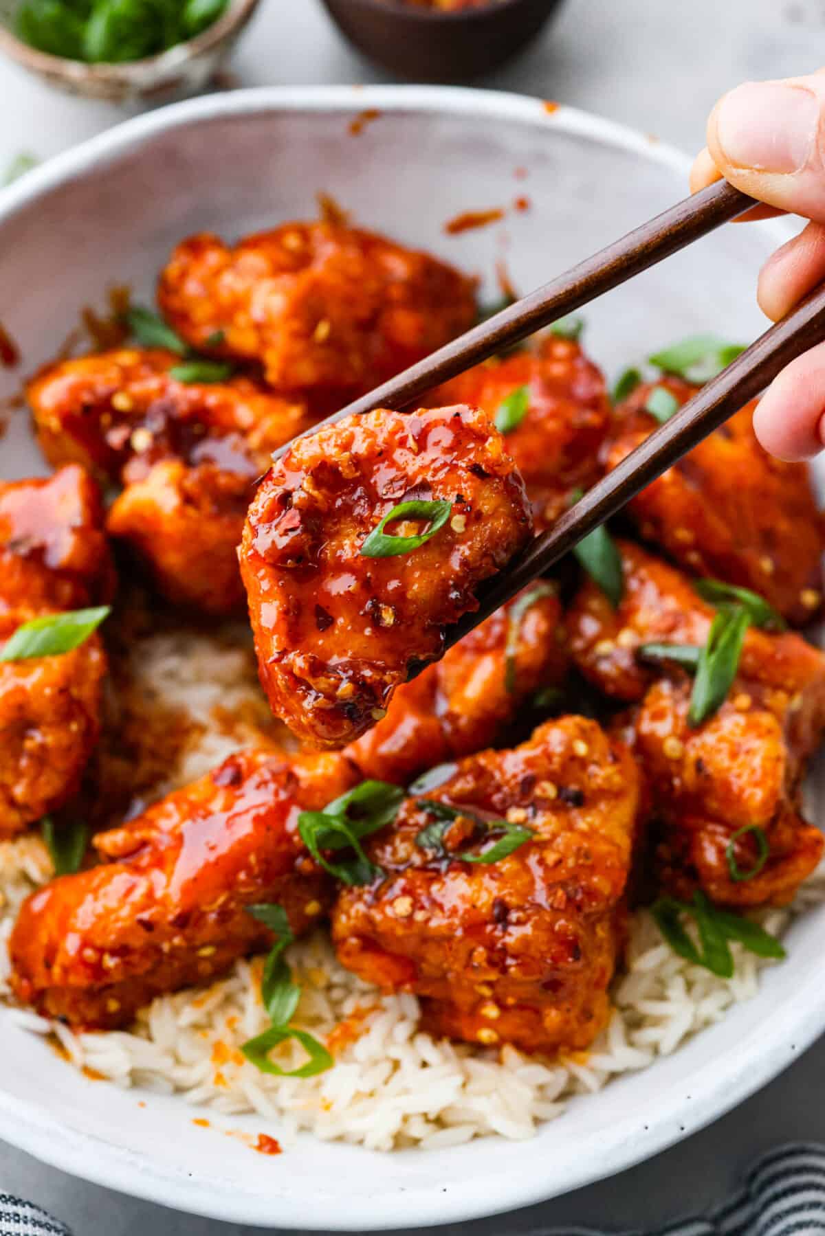Korean fried chicken or yangnyeom chicken has juicy breaded chicken tossed in a sweet and spicy glaze, itโs what dreams are made of! Gochujang paste gives it its classic spicy flavor, but the added honey and brown sugar tones it down enough that the whole family will love it. One bite and you'll be addicted! Picking up a piece of Korean fried chicken.