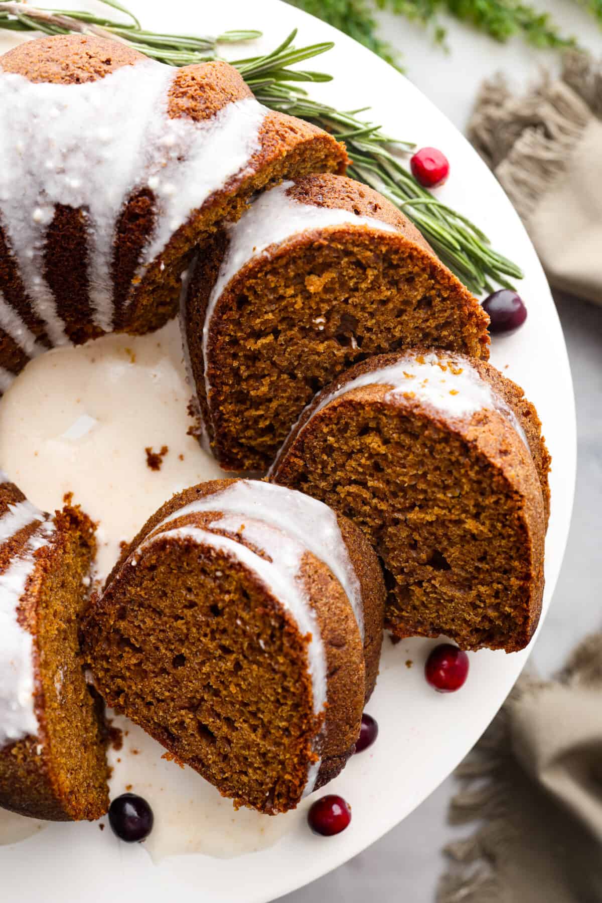 Festive Gingerbread Bundt Cake is moist, tender and the perfect dessert for the holidays. Topped with a flavorful brown butter maple glaze, youโll welcome a slice any time of day. Top-down view of a gingerbread bundt cake, cut into slices.