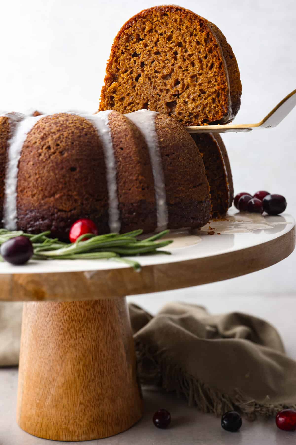 Festive Gingerbread Bundt Cake is moist, tender and the perfect dessert for the holidays. Topped with a flavorful brown butter maple glaze, youโll welcome a slice any time of day. A slice of cake being served with a metal spatula.