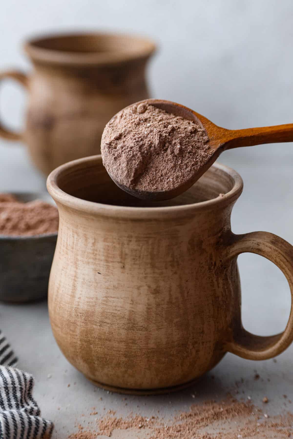 Delicious homemade hot chocolate mix that you can enjoy all winter long! It’s easy to customize and makes a perfectly rich and creamy cup of hot cocoa every time. Pouring a spoonful of hot chocolate mix into a mug.