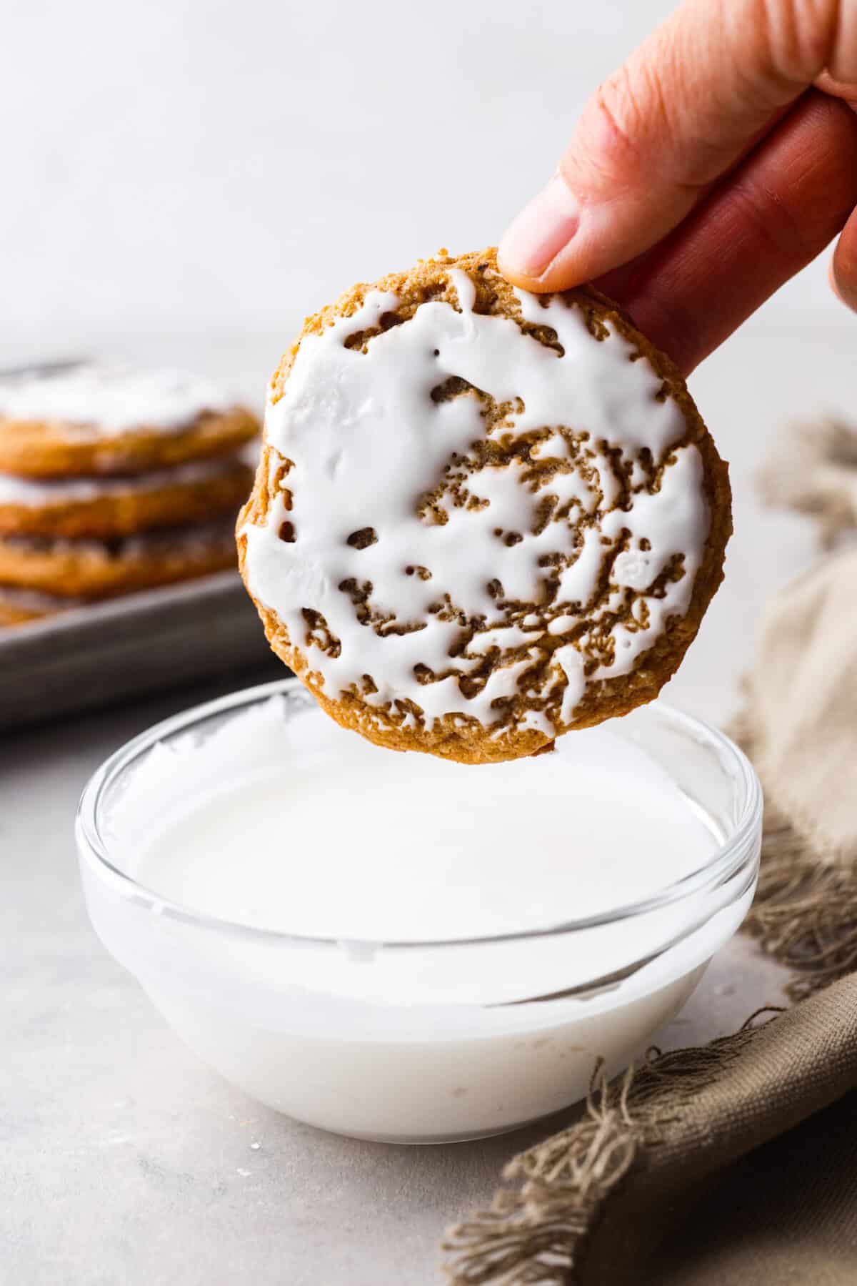 Perfect for the holidays, these iced oatmeal cookies are soft, moist, and packed with cinnamon and nutmeg for cozy spiced flavor. Topped with a layer of homemade icing, you'll love every bite! An iced oatmeal cookie, after being dipped in the glaze.