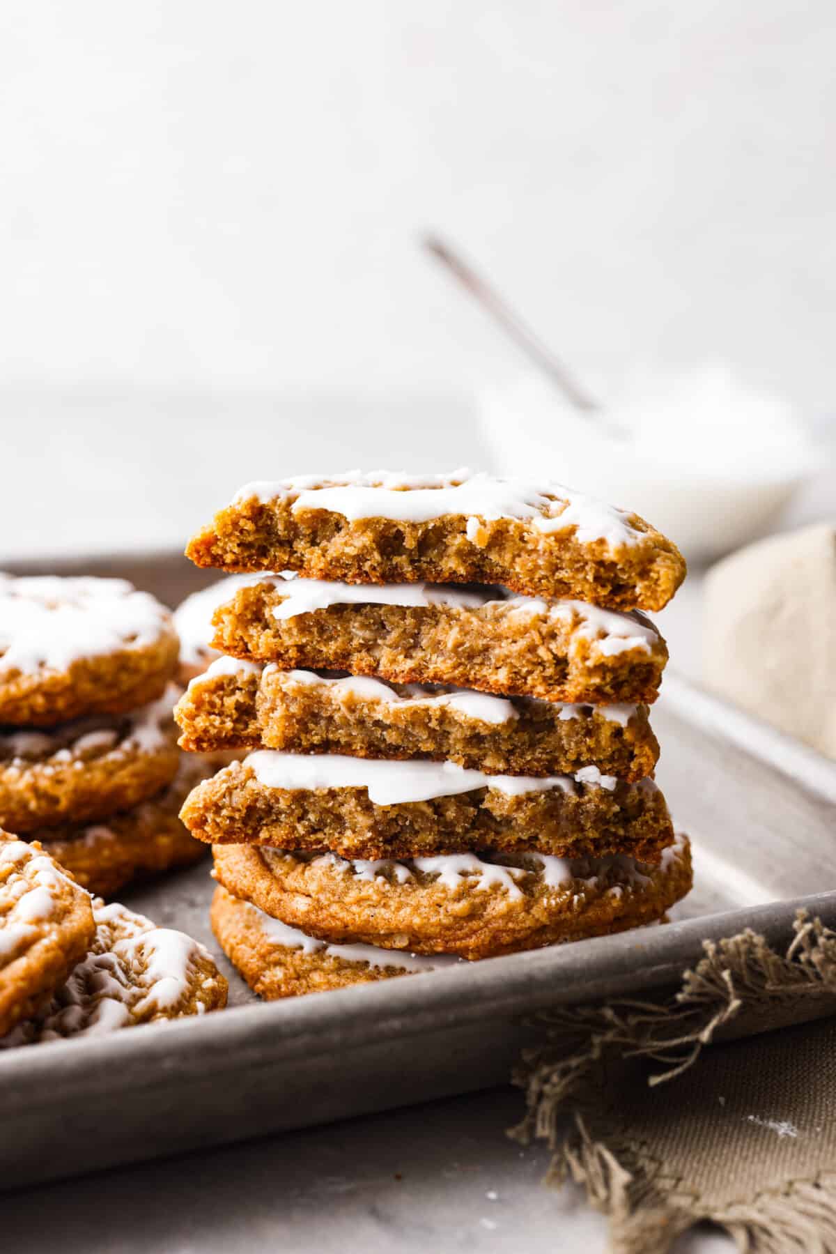Perfect for the holidays, these iced oatmeal cookies are soft, moist, and packed with cinnamon and nutmeg for cozy spiced flavor. Topped with a layer of homemade icing, you'll love every bite! 6 cookies stacked on top of each other. Some are broken in half.