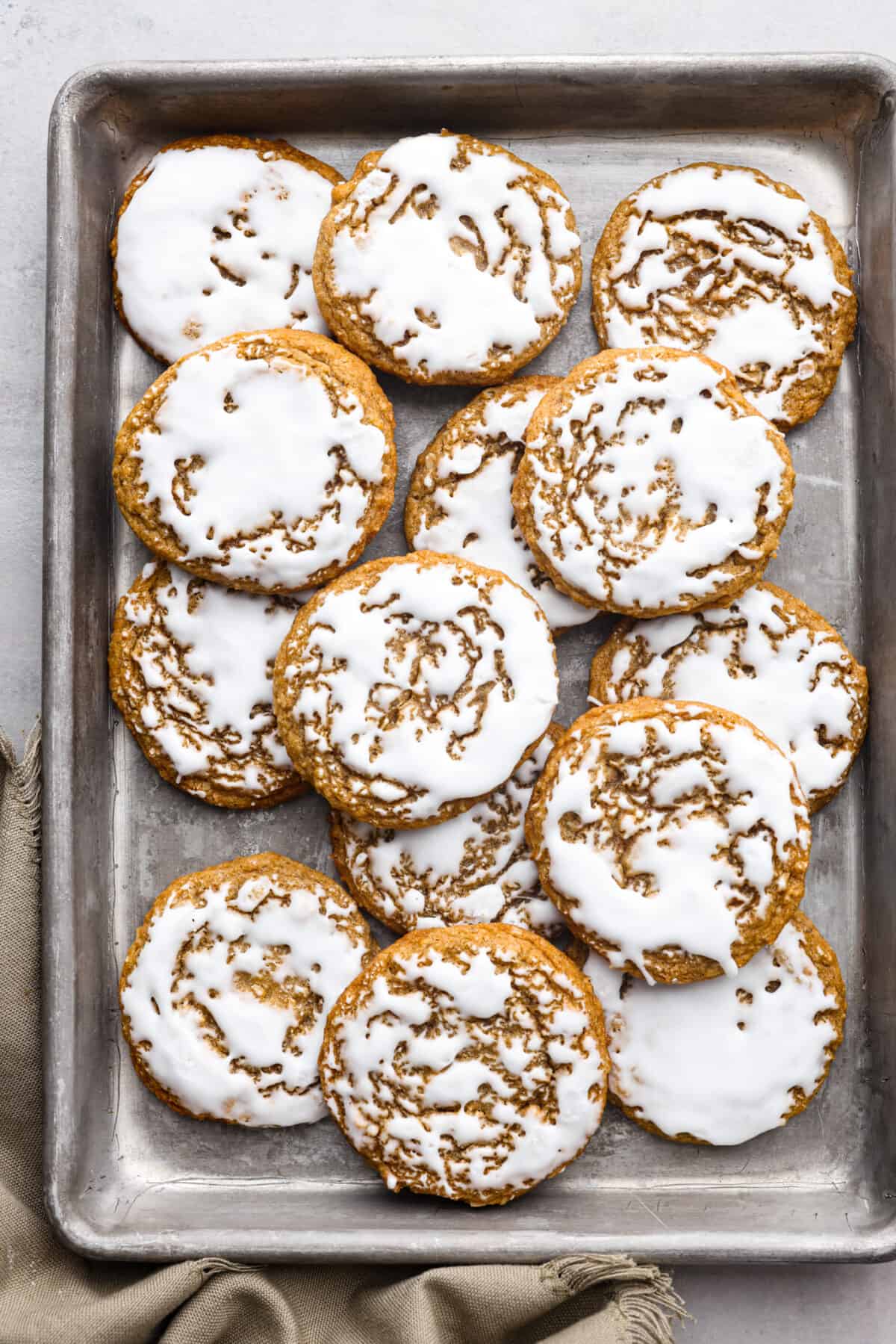 Perfect for the holidays, these iced oatmeal cookies are soft, moist, and packed with cinnamon and nutmeg for cozy spiced flavor. Topped with a layer of homemade icing, you'll love every bite! Top-down view of iced oatmeal cookies in a pan.