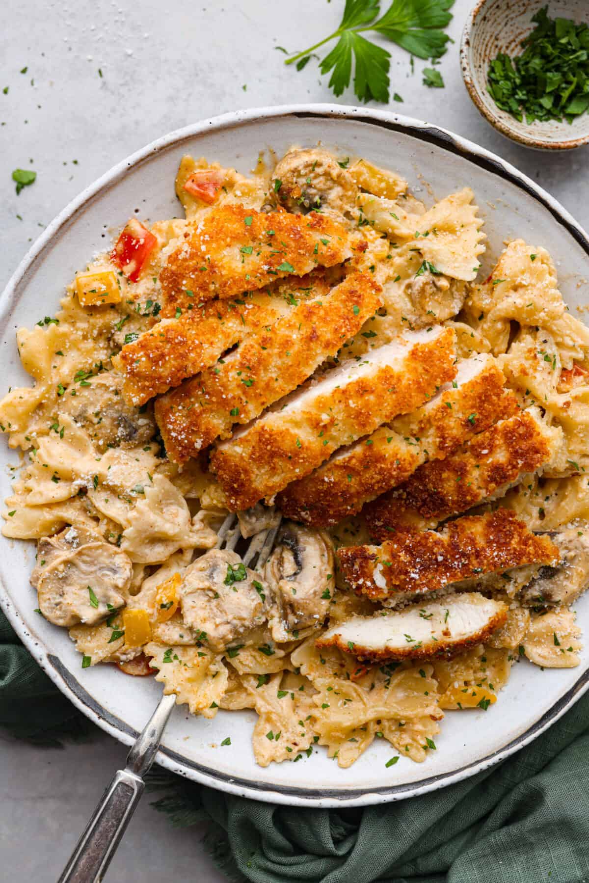Breaded, crispy chicken cutlets and a creamy Cajun sauce come together in this AMAZING Louisiana chicken pasta recipe. Inspired by Cheesecake Factory, you're going to love making this at home! Sliced, breaded chicken served over bow tie pasta with a creamy Cajun sauce.
