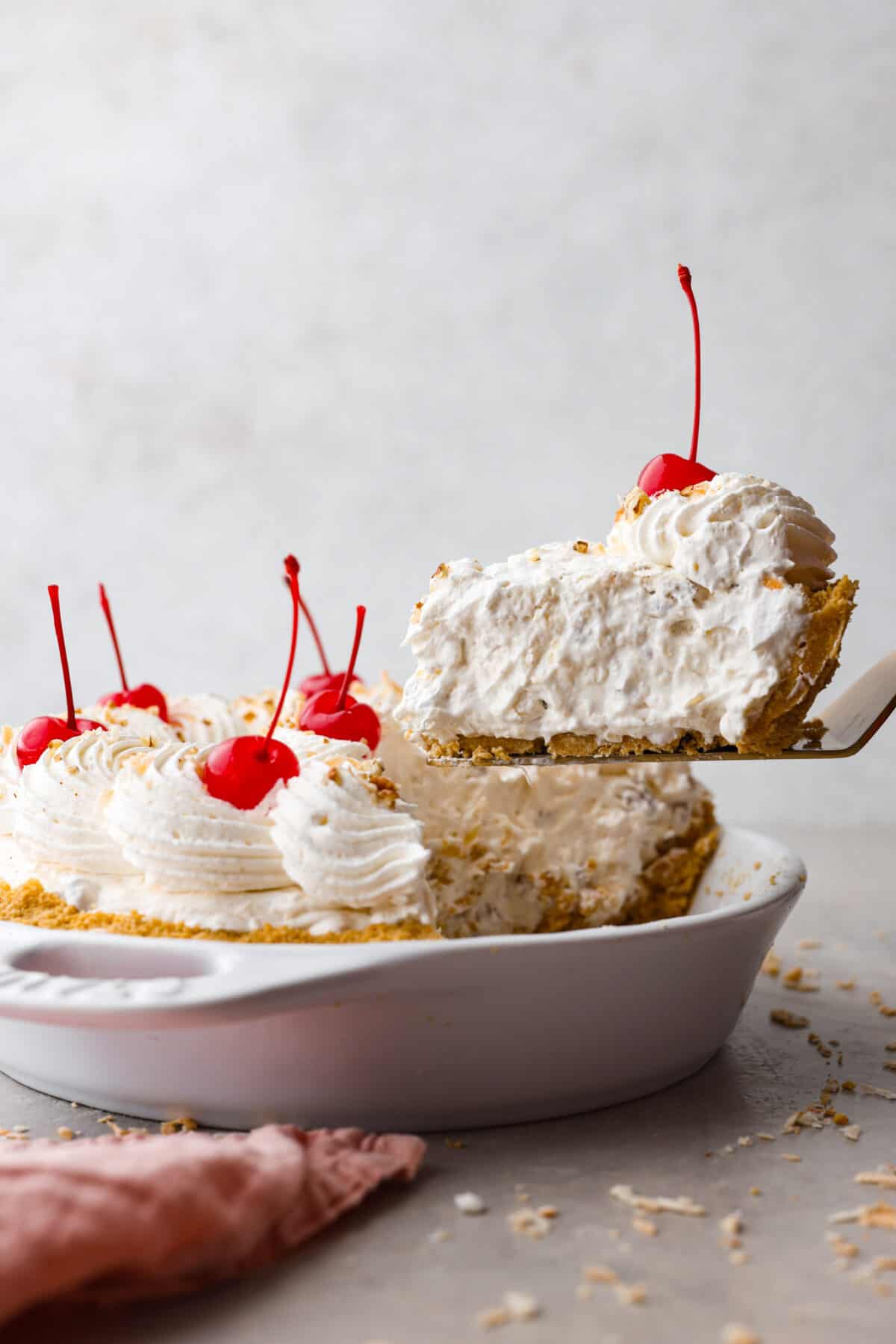 Named 'Million Dollar Pie' because it's so rich and delicious, this scrumptious dessert is the perfect way to satisfy your sweet tooth! It's light and fluffy but packed with coconut, pecans, and pineapple for tasty tidbits in each bite! Serving a slice of million dollar pie with a metal cake spatula.