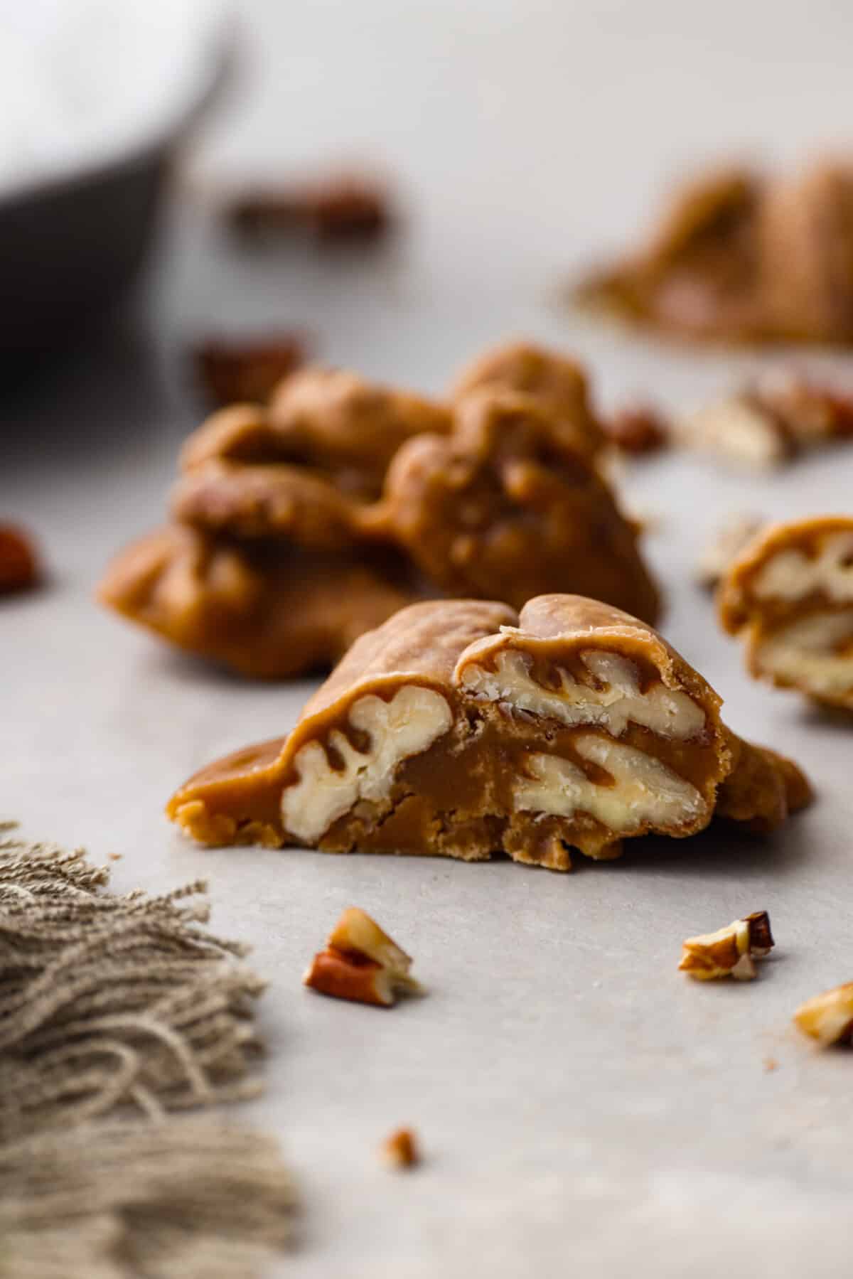 If you have a sweet tooth, this Pecan Praline recipe is for you! An ooey gooey combination of sweet flavors and a crunchy texture, this recipe is perfect for any occasion. A close up of the side vew of a slice pecan praline.