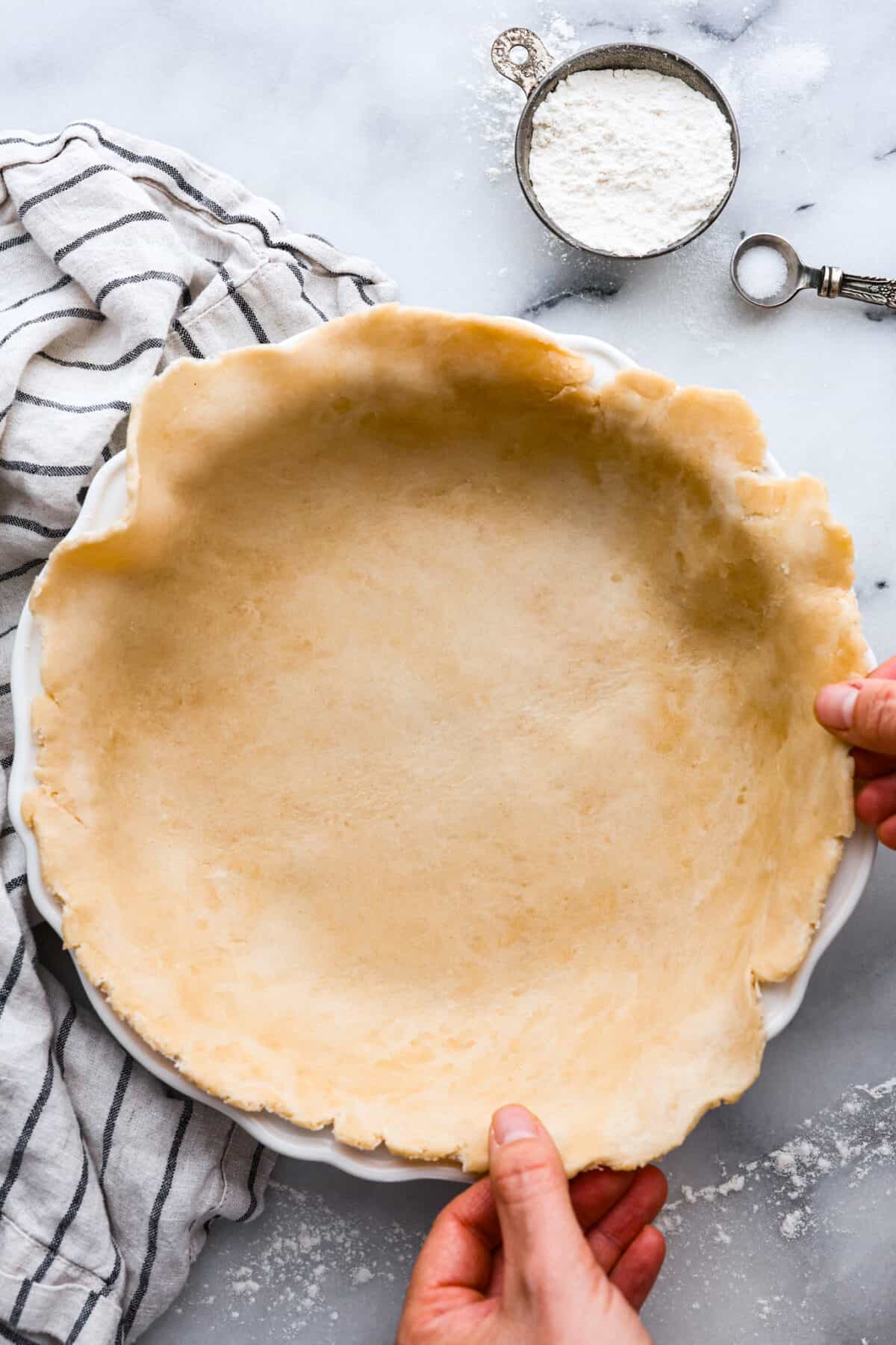 Grandma's famous pumpkin pie is smooth, thick, and creamy! A MUST for the holidays and the best when served with a big dollop of whipped cream on top! Placing a homemade, unbaked crust in a pie pan.