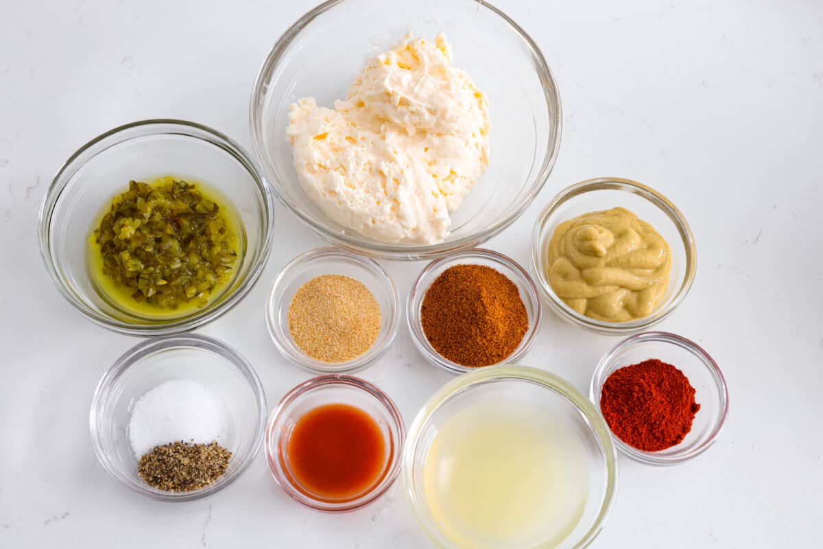 Remoulade sauce, a tasty dip from Louisiana, is made with mayonnaise, mustard, hot sauce, relish, and some Cajun spices for the best flavor ever! Whether you use it as a dip or spread, you're going to love the kick of flavor it adds to your favorite recipes. All of the different sauce ingredients in small glass bowls.