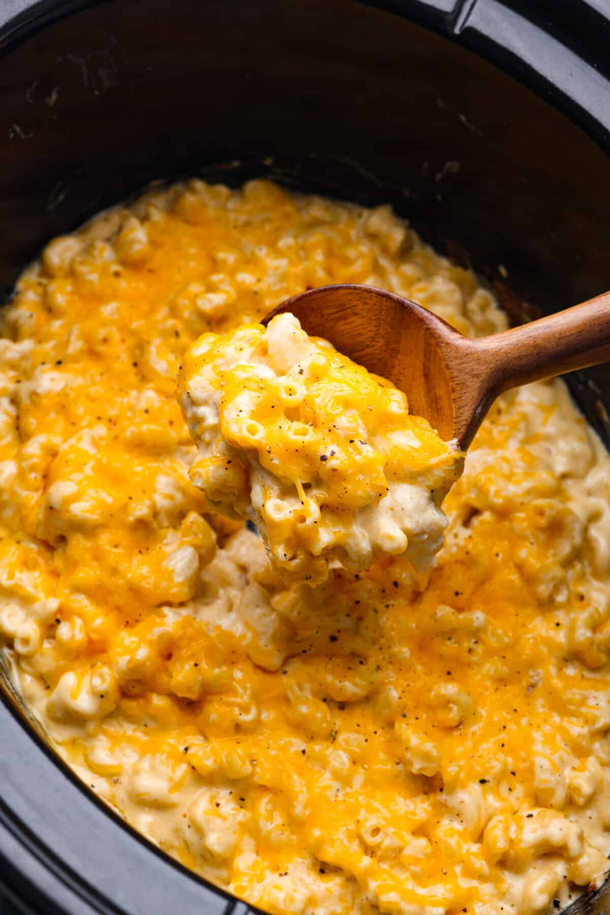 This Slow Cooker Macaroni and Cheese is creamy, comforting and perfect for potlucks. Best of all, it comes together easily in the crock-pot โ even the pasta! Closeup of a spoonful of pasta.