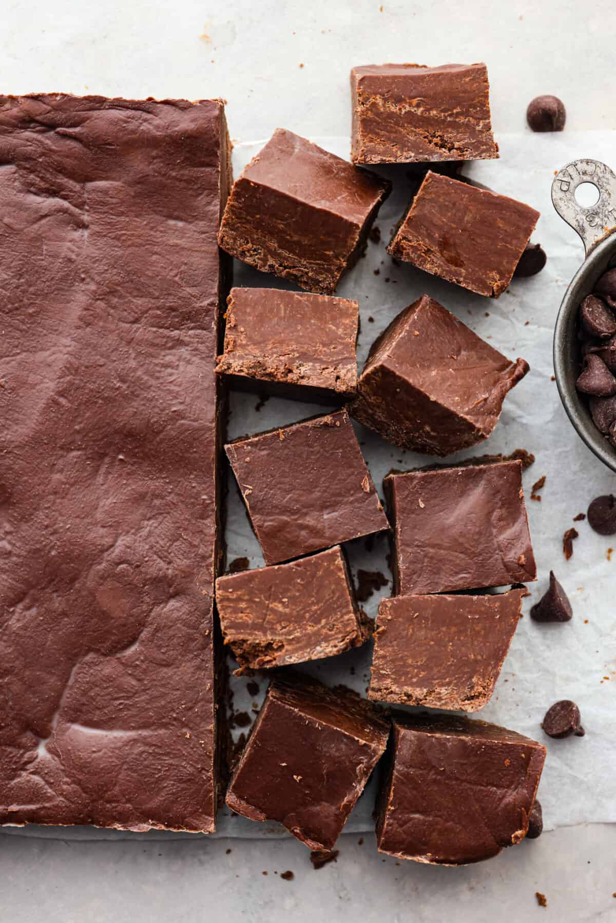 It doesn't get any easier than this homemade 2 ingredient fudge! Creamy and decadent fudge that only takes 5 minutes to make. Perfect for parties and gifting! Top view of 2 ingredient fudge cut into squares laying on parchment paper.