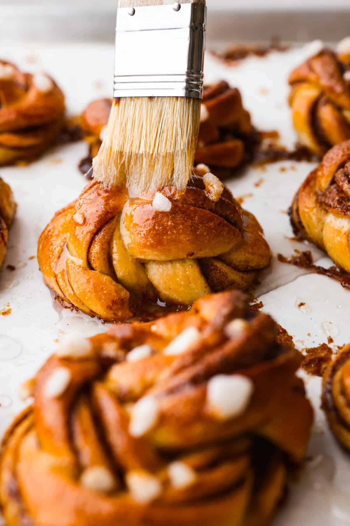 These Swedish cinnamon buns, also known as Kanelbullar, are just the dessert to make if you’re craving something soft, sweet, and spiced to perfection! You’re not going to be able to resist going in for another bite, especially if they’re fresh out of the oven! Brushing an egg wash on the buns.