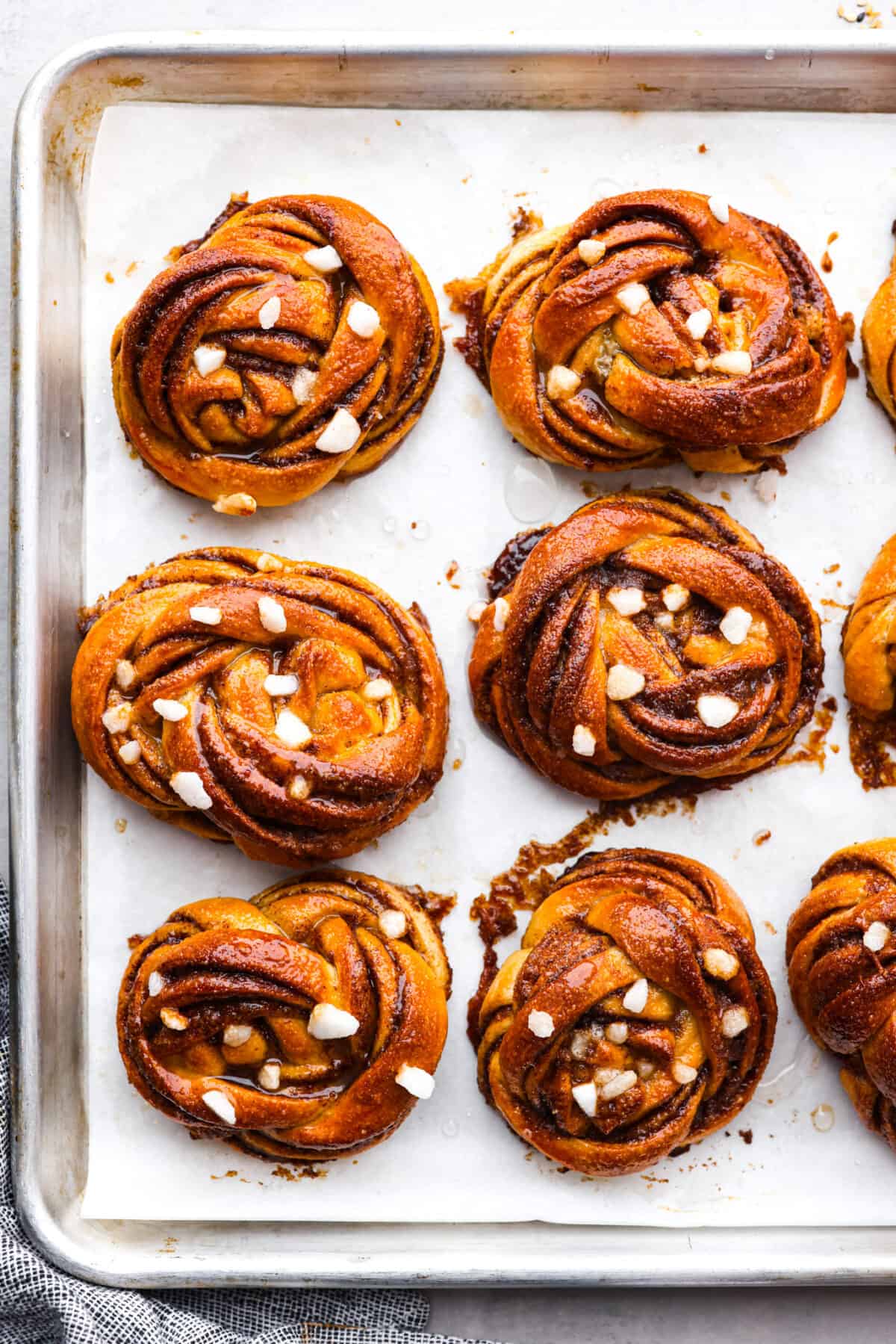 These Swedish cinnamon buns, also known as Kanelbullar, are just the dessert to make if you’re craving something soft, sweet, and spiced to perfection! You’re not going to be able to resist going in for another bite, especially if they’re fresh out of the oven! Kanelbullar on a baking sheet lined with parchment paper.