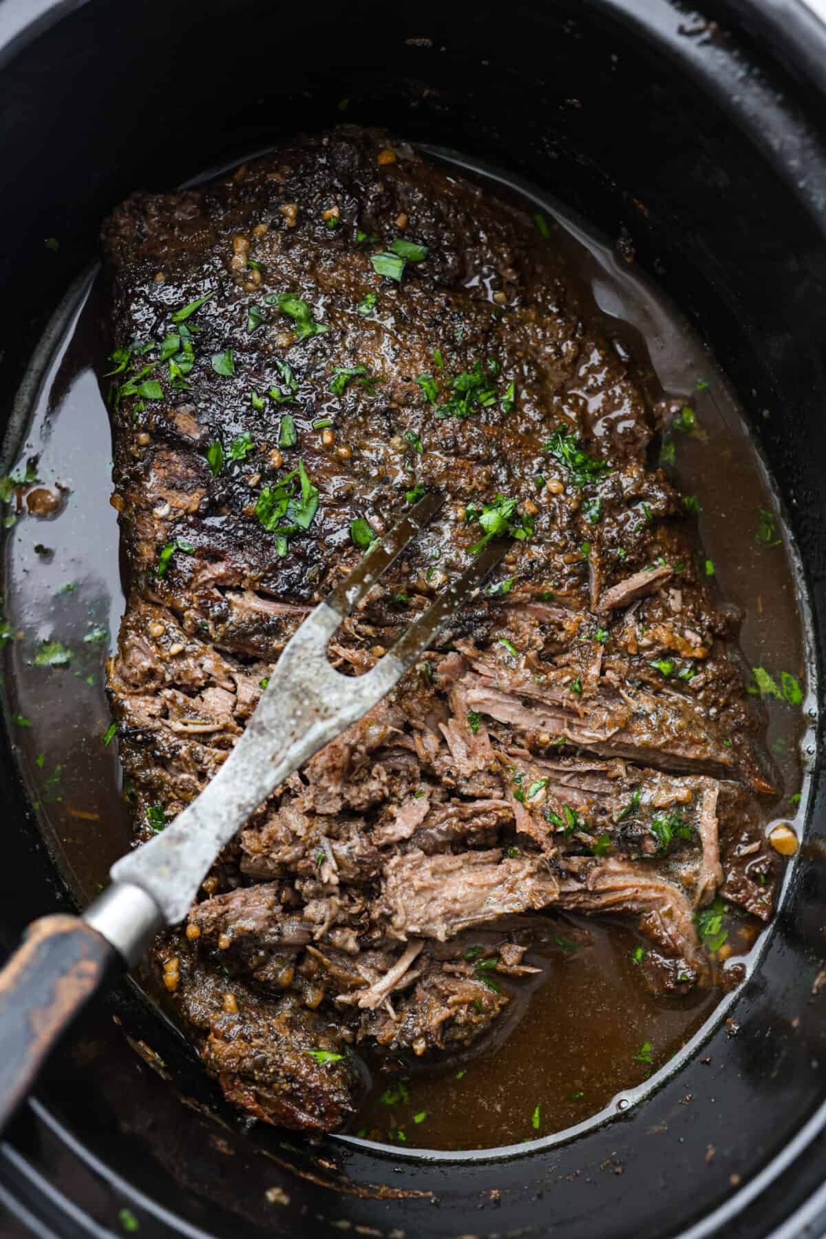 Tender and juicy, this Slow Cooker Balsamic Beef is absolutely incredible! Add everything to your crockpot in the morning, then in the evening, you'll have sweet and savory, tangy balsamic beef ready for dinner. Balsamic beef being shredded in the bottom of a slow cooker.