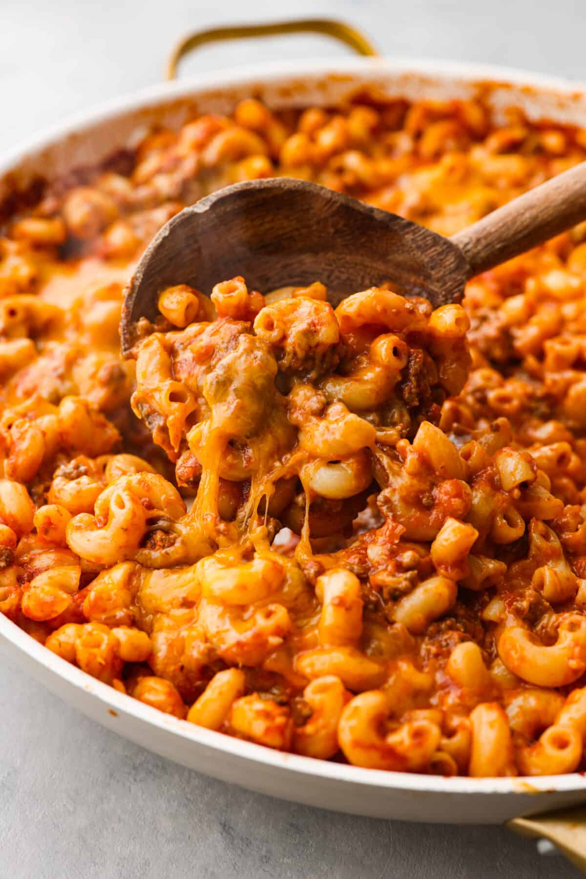 Craving cheesy, saucy comfort food that's perfect for a weeknight meal? This hearty beefaroni is the way to go. Each macaroni noodle traps the cheesy, meaty, garlicky sauce inside, so every bite has incredible flavor. Easy to prepare and picky eater-approved, this is one dinner you don't want to miss out on. Closeup of a scoop of beefaroni in a wooden spoon.