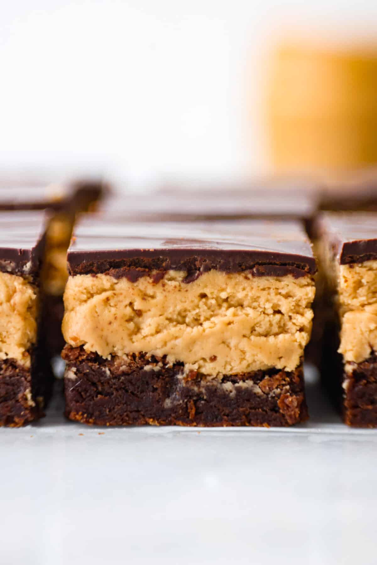 Buckeye brownies are known for their three layers of rich decadent goodness! A fudgy brownie base gets a sweet peanut butter layer then topped with chocolate ganache. It's a chocolate peanut butter lover's dream brownie! Close view of buckeye brownies showing the three decadent layers.