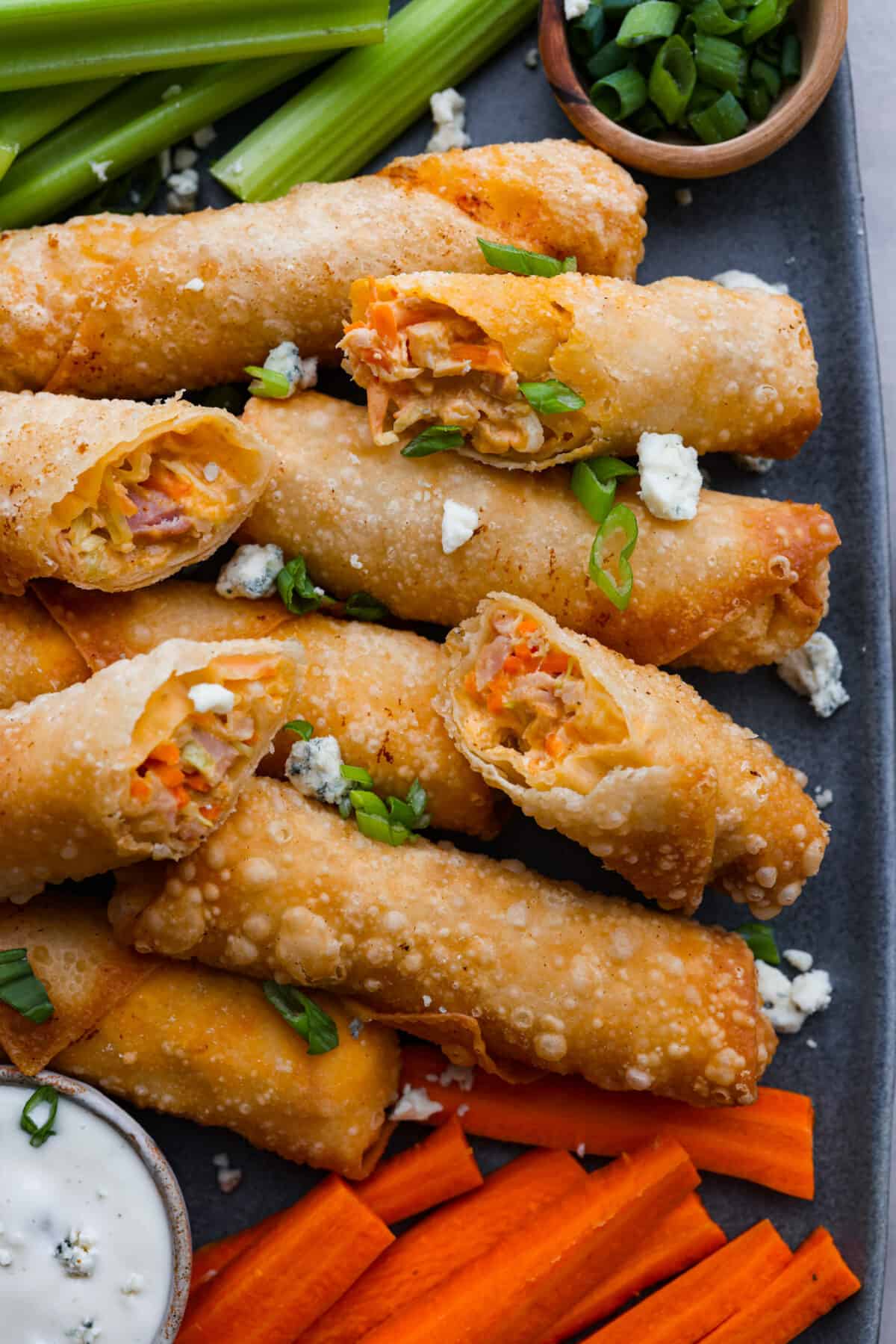 Wait until you taste these Buffalo Chicken Egg Rolls' crispy texture and bold flavors! A delicious mixture of cream cheese, hot sauce, and spices envelops shredded chicken, carrots, and cabbage, creating a perfect balance of crunch and zing. Buffalo Chicken Egg Rolls on a platter.