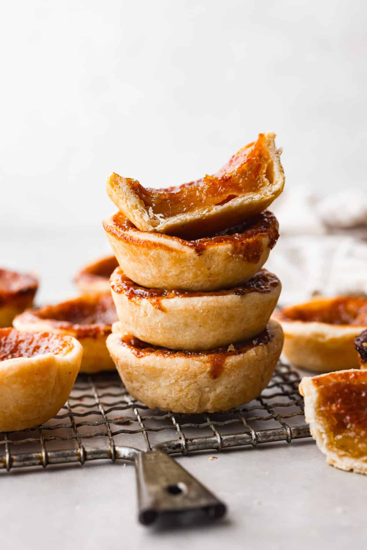 Rich and gooey Butter Tarts are the perfect treat for any occasion! They feature a sweet, buttery filling baked inside a flaky crust that will definitely make you want to keep going back for more!ย 4 tarts stacked on top of each other. One is cut in half so you can see the filling.