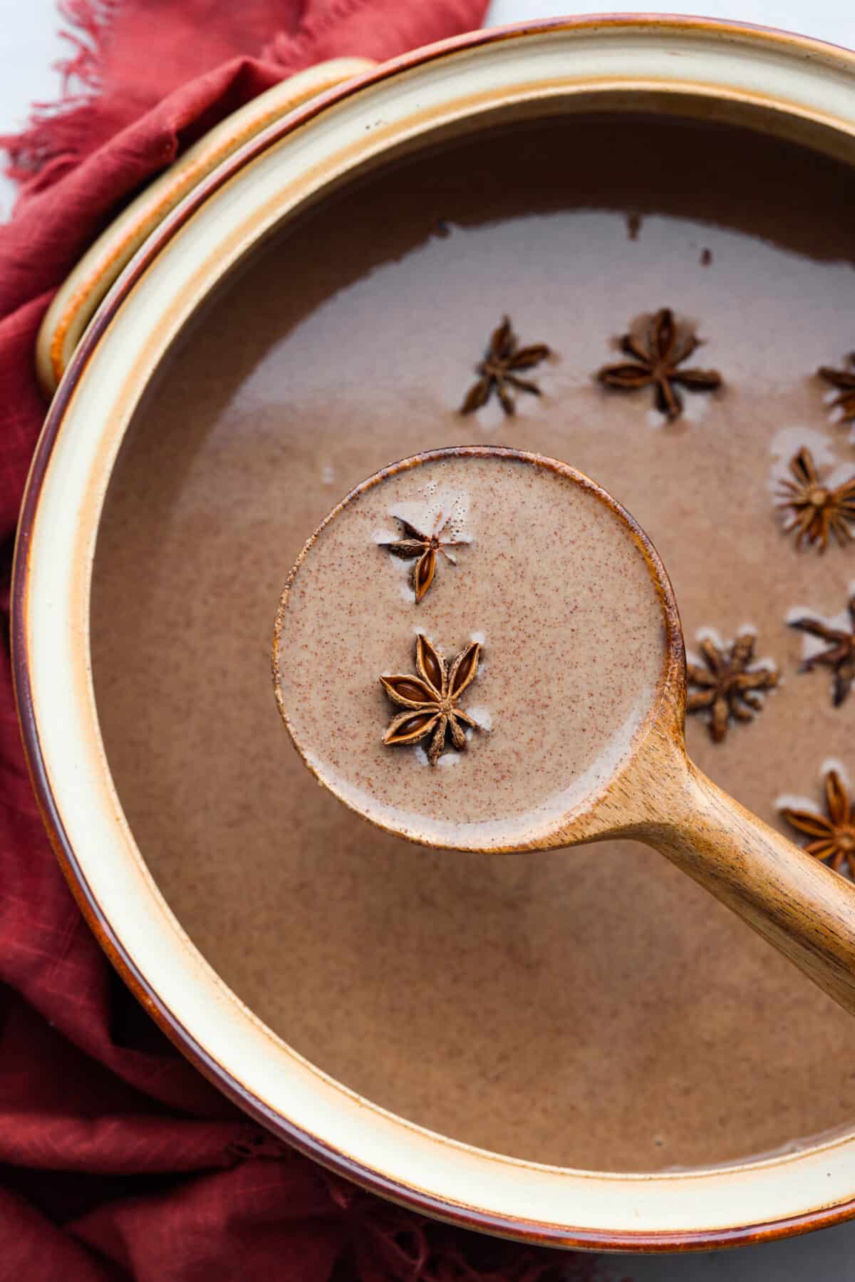 Get toasty from the inside out with champurrado, a delicious variation of Mexican hot chocolate! Deep, melty chocolate meets warming spices and brown sugar, all thickened with corn flour for a velvety smooth sip. Perfect for chasing any winter blues away! A pot of champurrado being served with a wooden ladle.