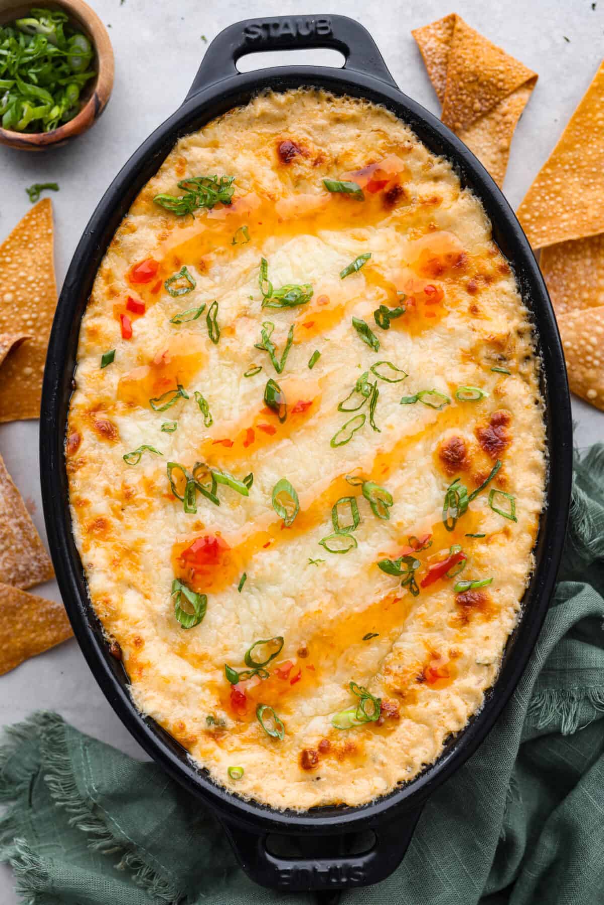 We are obsessed with this crab rangoon dip! It’s hot, creamy, cheesy and packed with crab and major flavor. It's sure to become your go-to appetizer when you really want to impress! Top-down view of the baked dip in a casserole dish.