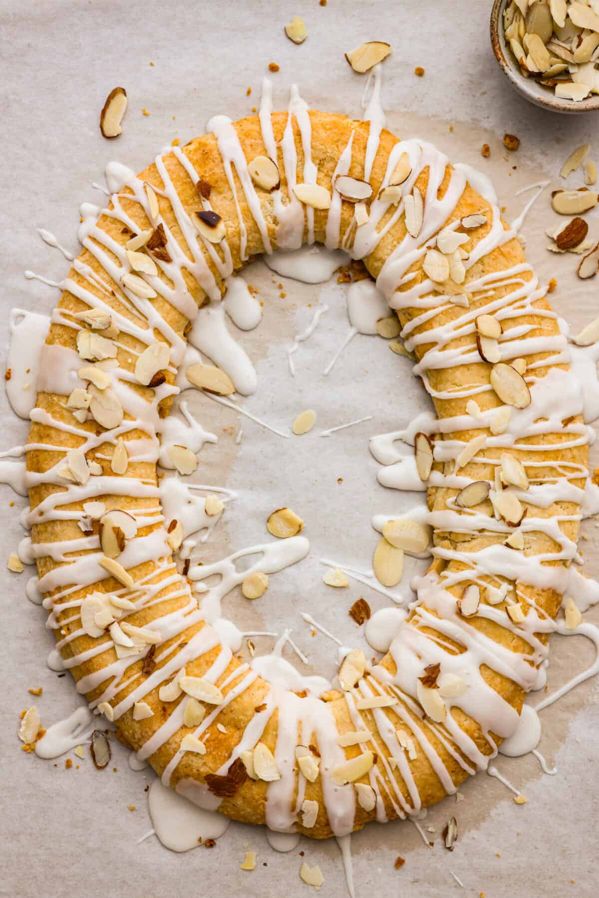This Danish Kringle is full of almond flavor, baked until golden, and then drizzled with a vanilla glaze. This can be eaten for breakfast or dessert, and everyone will love it! The top view of a full oval of Danish Kringle.