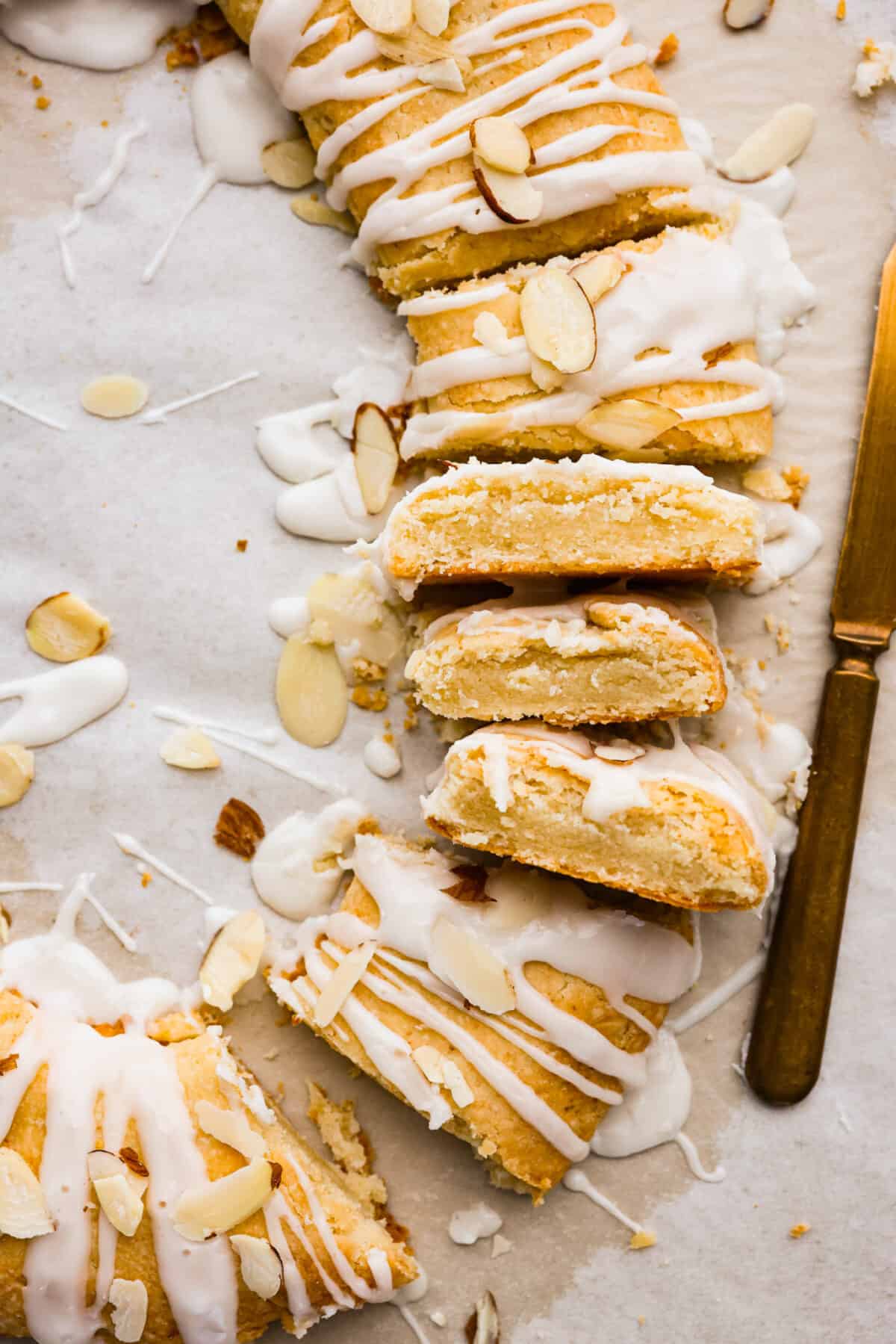 This Danish Kringle is full of almond flavor, baked until golden, and then drizzled with a vanilla glaze. This can be eaten for breakfast or dessert, and everyone will love it! A close up of a Danish Kringle that has been cut into slices.