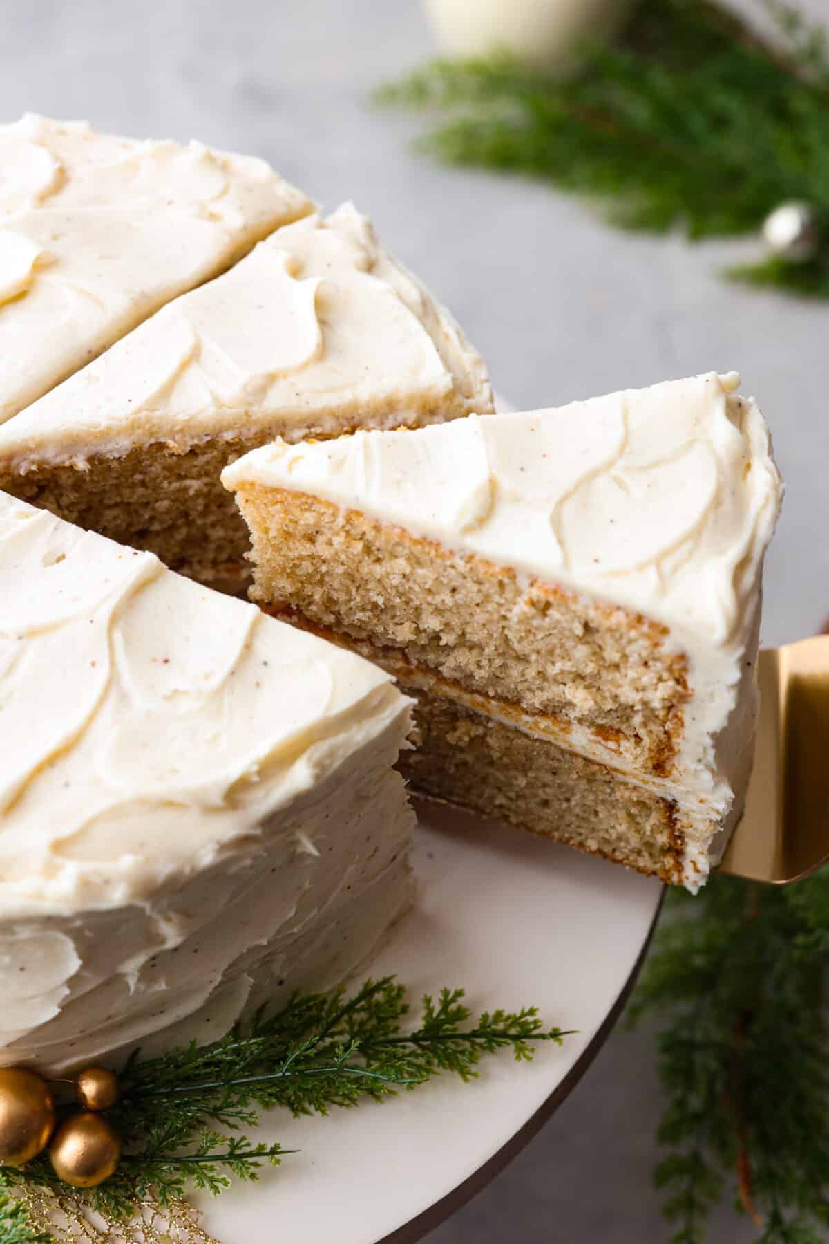 Festive eggnog cake is the perfect dessert to serve this holiday season! Make this moist eggnog-flavored cake bursting with delicious seasonal spices and layered with creamy eggnog buttercream! Top side view of a slice of eggnog cake on a cake spatula.