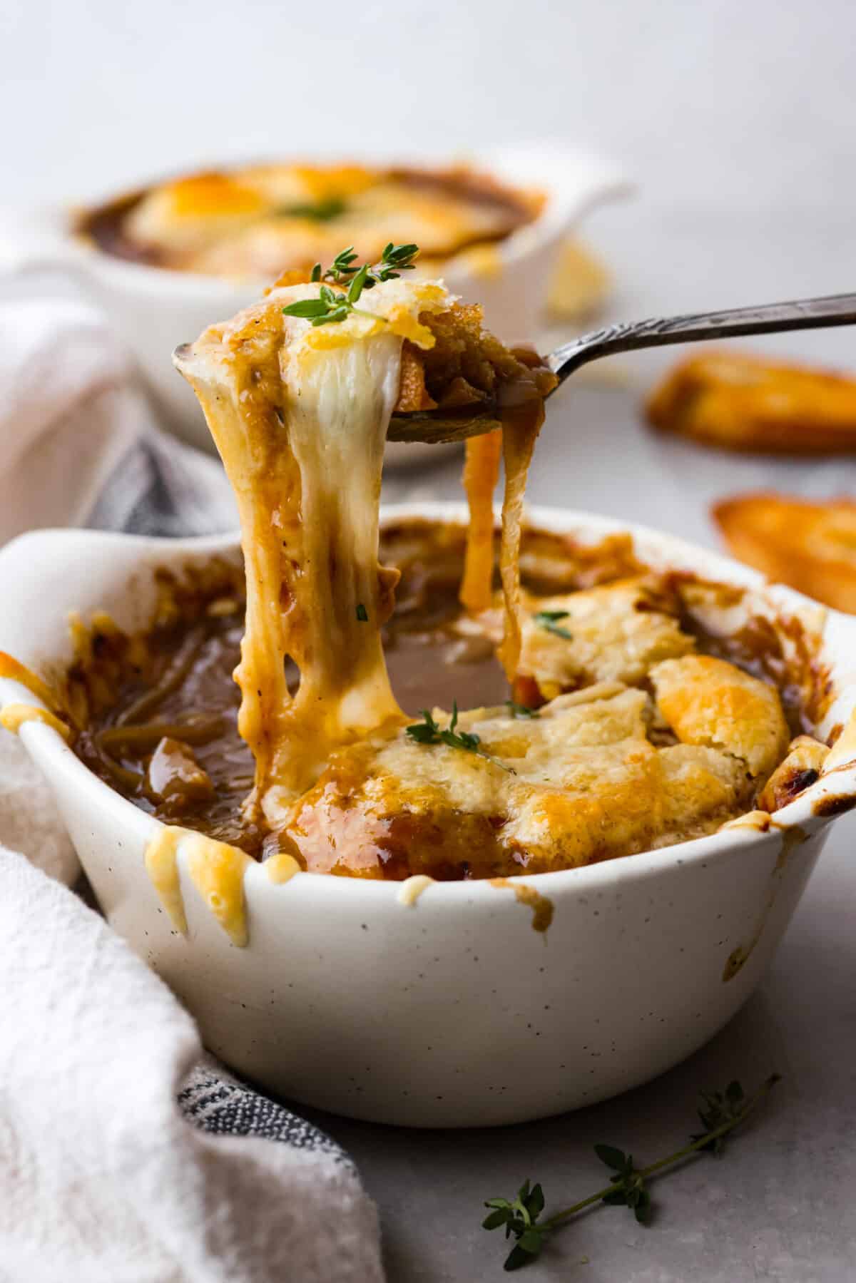 French Onion Soup is such a classic and SO easy to make! Onions are slowly caramelized until soft and sweet, simmered with beef broth, thyme, sherry, and white wine. It's topped with a crispy crouton, loads of shredded gruyere cheese and broiled into a crispy, cheesy oblivion. So good! A bowl of French onion soup.