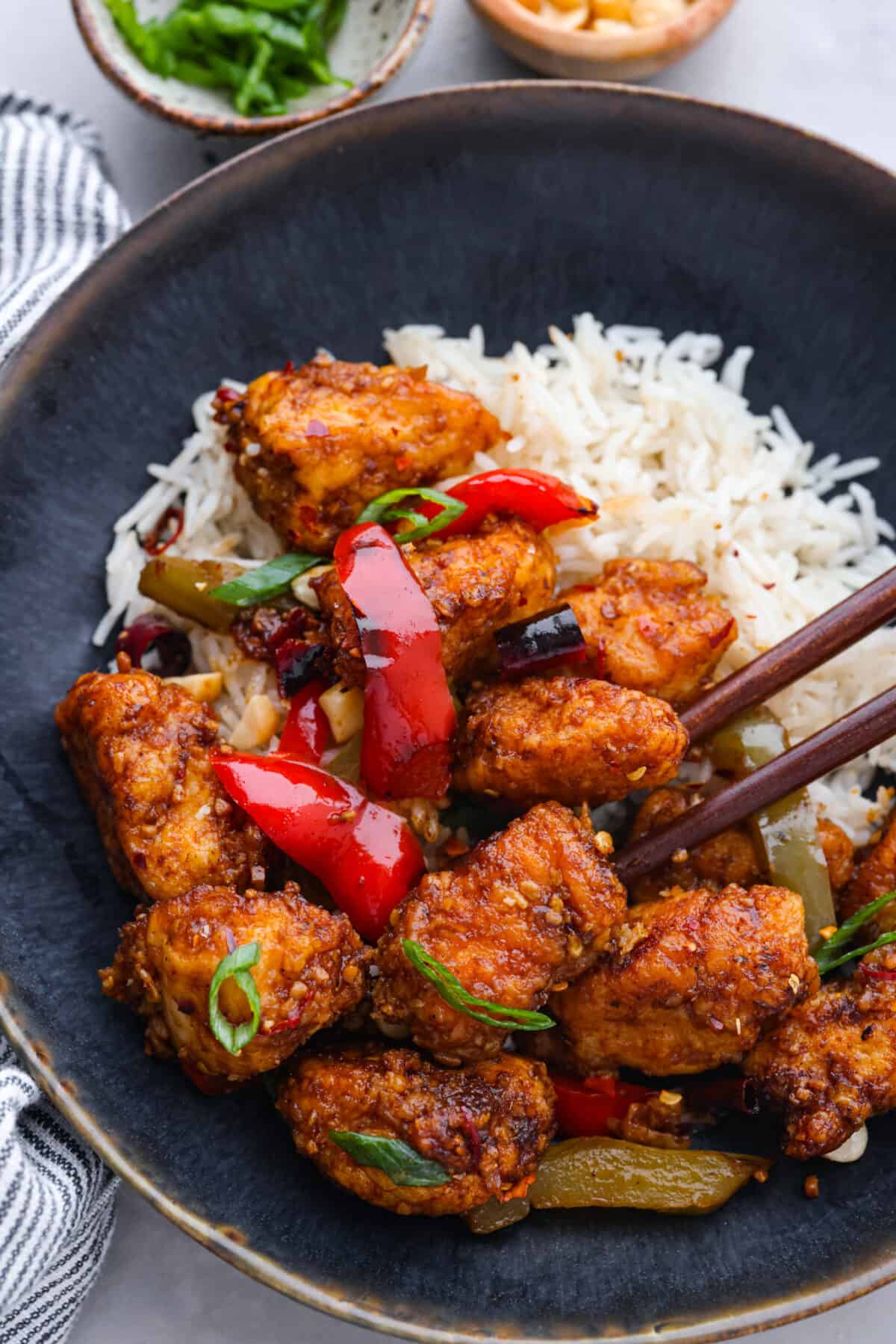 A takeout favorite for good reason! Kung pao chicken is pan-fried to crispy perfection and coated in a spicy, savory sauce that will leave you wanting more. Once you try making it from scratch, you won’t want it any other way! A serving of chicken and rice in a black bowl.