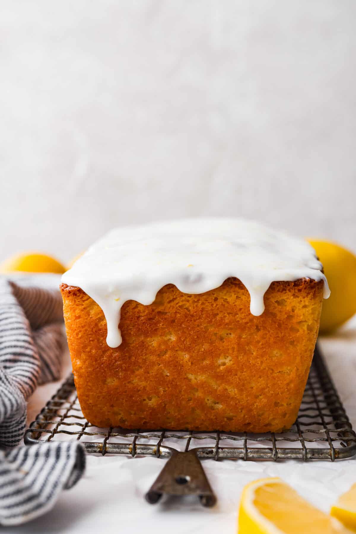 Bring the irresistible taste of Starbucks Lemon Loaf to your home with this easy-to-make recipe. A perfect blend of zesty lemon and moist texture, topped with a simple lemon icing โ enjoy the homemade version of this beloved Starbucks treat! The side view of glaze dripping off a loaf of bread.