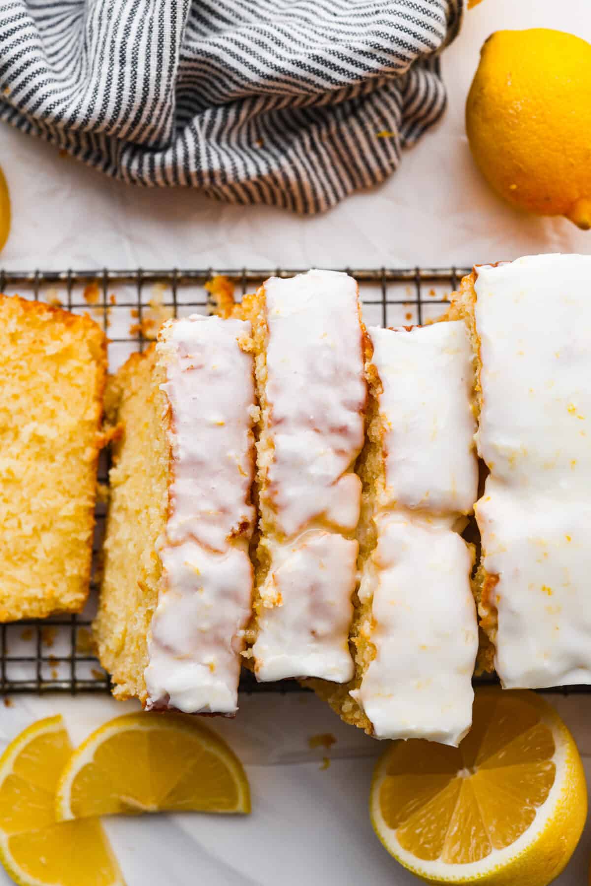 Bring the irresistible taste of Starbucks Lemon Loaf to your home with this easy-to-make recipe. A perfect blend of zesty lemon and moist texture, topped with a simple lemon icing โ enjoy the homemade version of this beloved Starbucks treat! The top view of slices Starbucks lemon loaf on a cooling rack with a white glaze on top.