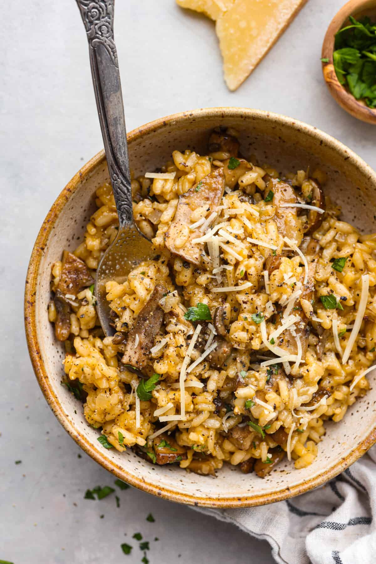 A creamy, hearty side dish that you'll want to serve with everything. Mushroom risotto is made with tender sauteed mushrooms and arborio rice simmered to perfection in a garlic, shallot, and white wine sauce. Top it off with some shredded parmesan for a tasty dish that will rival the main course! A serving of risotto in a stoneware bowl.