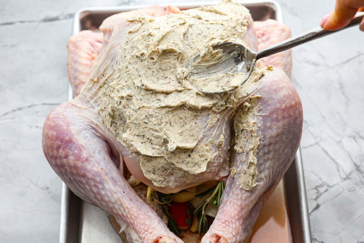 Look no further! This roasted turkey recipe is the absolute juiciest, fool-proof turkey recipe you will ever need. You'll have the confidence to make a perfect turkey every time. This deliciously seasoned turkey will be the star of your Thanksgiving meal! Seventh photo of the herb butter spreading on the turkey.
