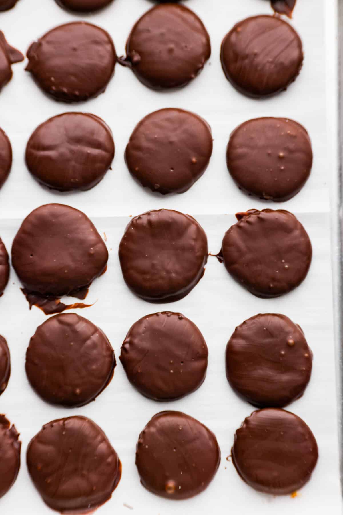 These homemade peppermint patties are miles ahead of anything you'll find at the store, and making them is a breeze. They're soft and pillowy, packed with mint chocolate flavor that will leave you wanting more! Top-down view of peppermint patties on parchment paper.