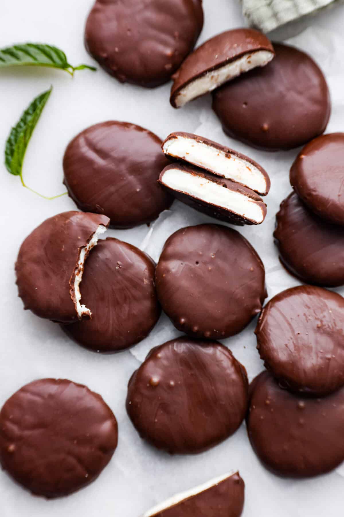 These homemade peppermint patties are miles ahead of anything you'll find at the store, and making them is a breeze. They're soft and pillowy, packed with mint chocolate flavor that will leave you wanting more! Top-down view of peppermint patties. Some are broken in half so the mint filling can be seen.